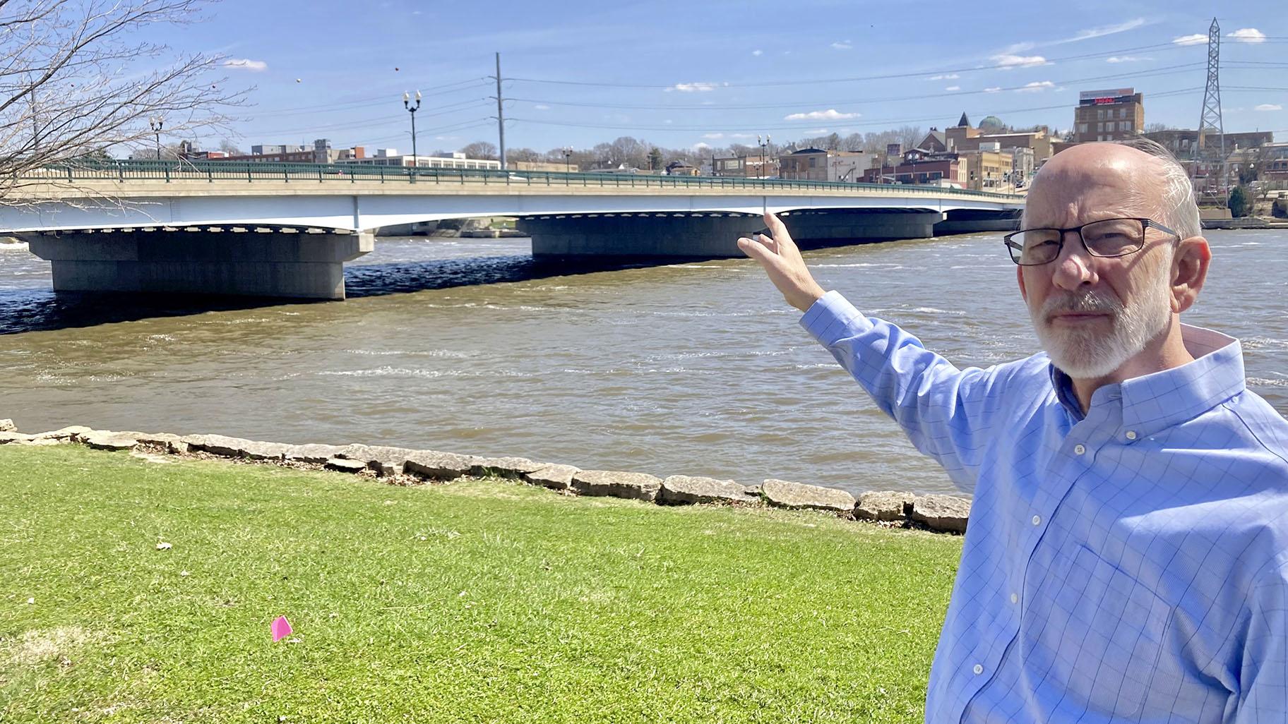 Tom Wadsworth gestures towards the Truesdell bridge while standing on the bank of the Rock River in Dixon, Ill., on Tuesday, April 11, 2023, near the site of the May 4, 1873, baptismal ceremony. (AP Photo / John O’Connor)