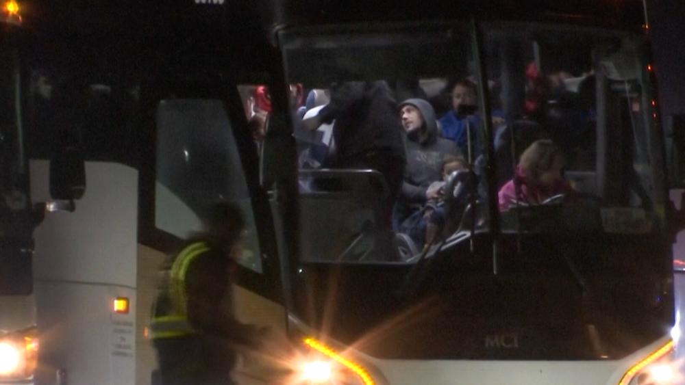 Migrants board a bus as they arrived on a plane from San Antonio at Chicago Rockford International Airport at 1am on Jan. 1, 2024 in Rockford, Ill. The city of Chicago said 355 migrants on the Boeing 777 boarded eight buses chartered by Abbott to be dropped off in "various suburbs." (WTVO NewsNation via AP)