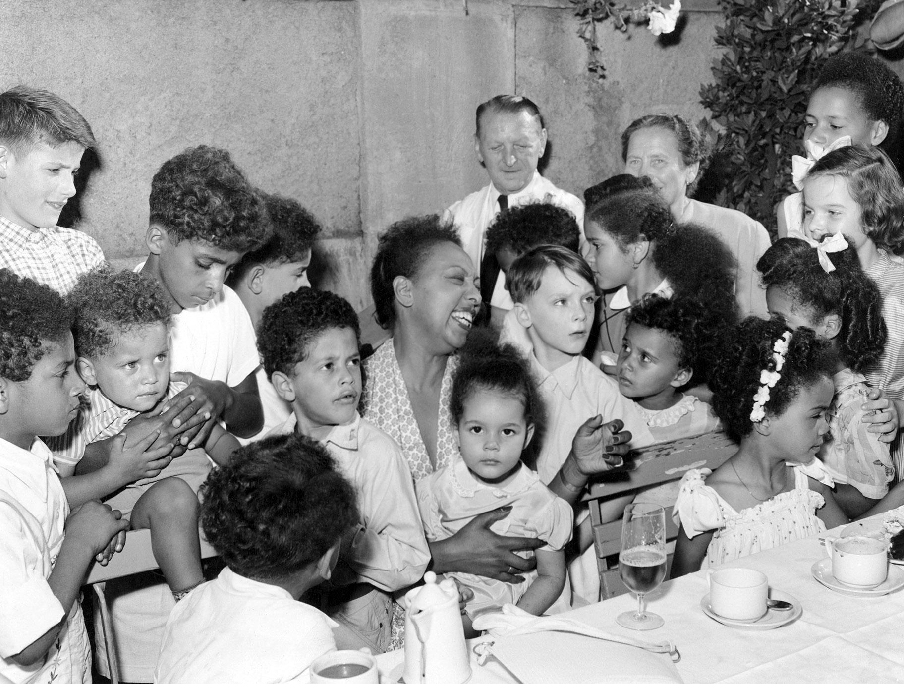 Well known American singer and dancer, Josephine Baker, who was in Berlin to play a role in German film, “An jeden Finger zehn” (Ten on Every Finger), on Aug. 3, 1954, was hostess to 40 children including orphans and local Black children, whom she treated with chocolate and cake at the zoo in West Berlin. (AP Photo / Heinrich Sanden Jr., File)