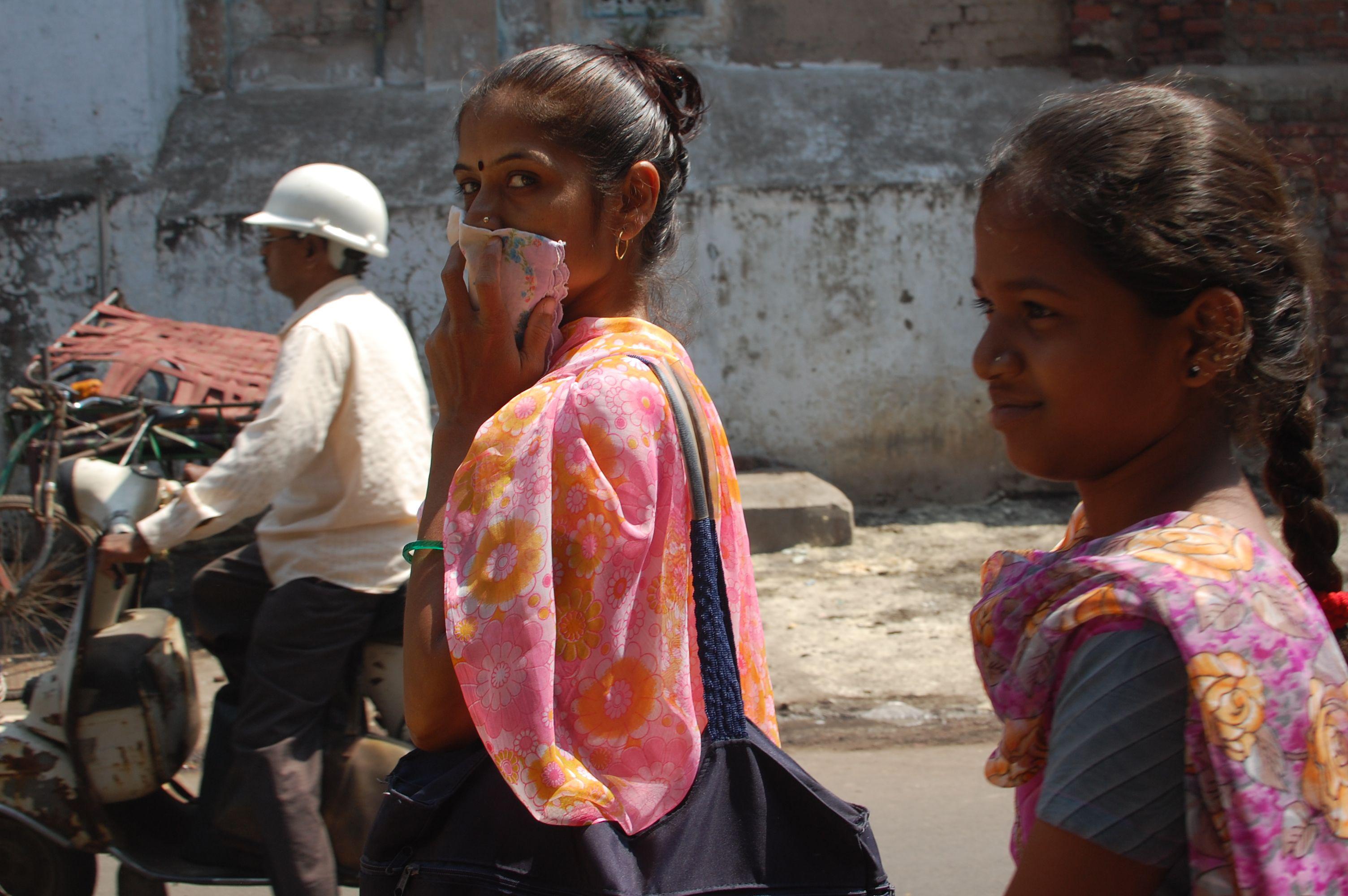 A woman covers her mouth with a handkerchief while walking through the streets of Ahmedabad, India. (Jill Ryan / WBUR Boston’s NPR News Station / Flickr)