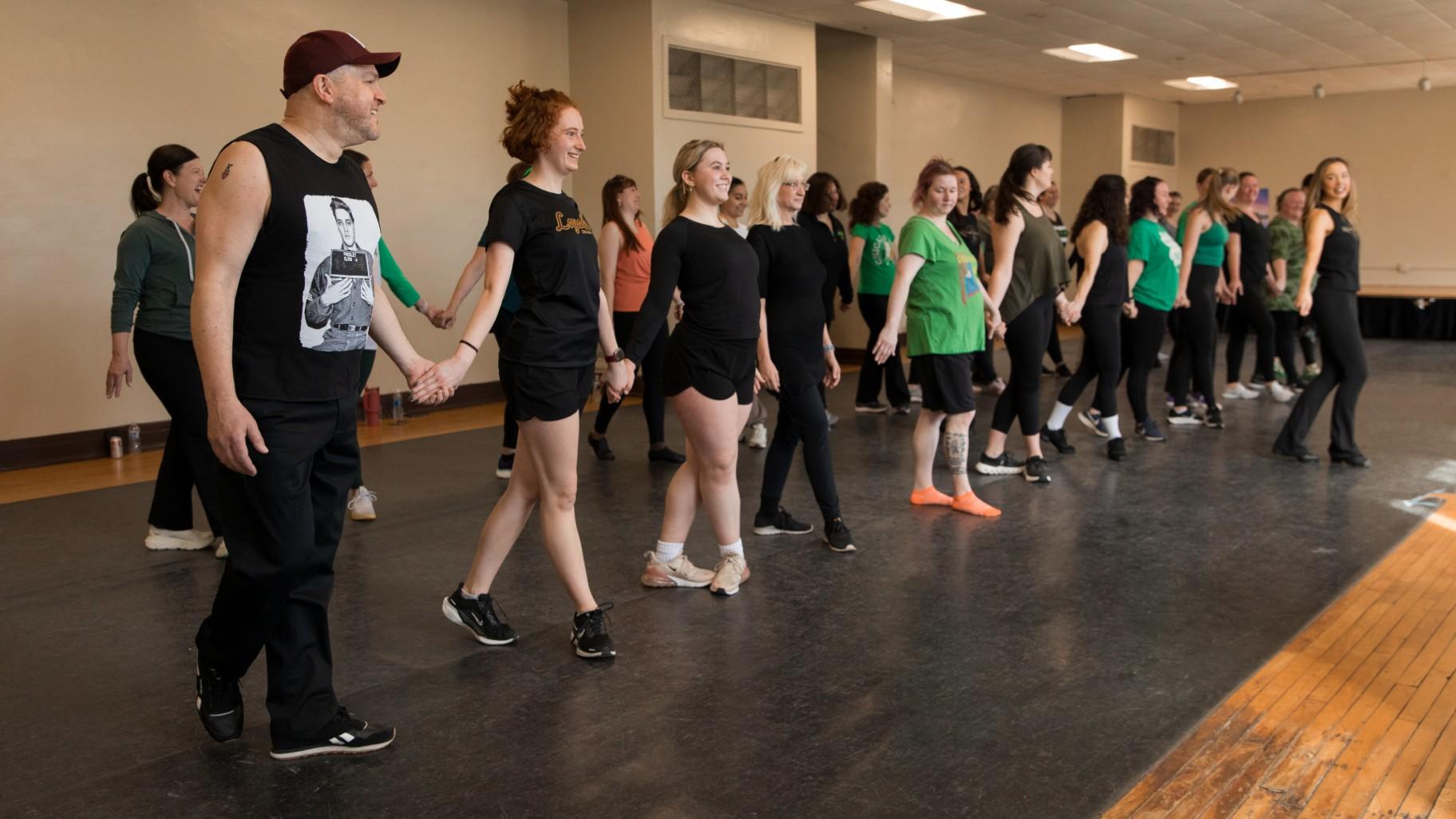 WTTW News arts reporter Marc Vitali, left, puts the wrong foot forward while taking an Irish dancing lesson at the Irish American Heritage Center, 4626 N. Knox Ave., on March 17, 2025. (Michael Izquierdo / WTTW News)