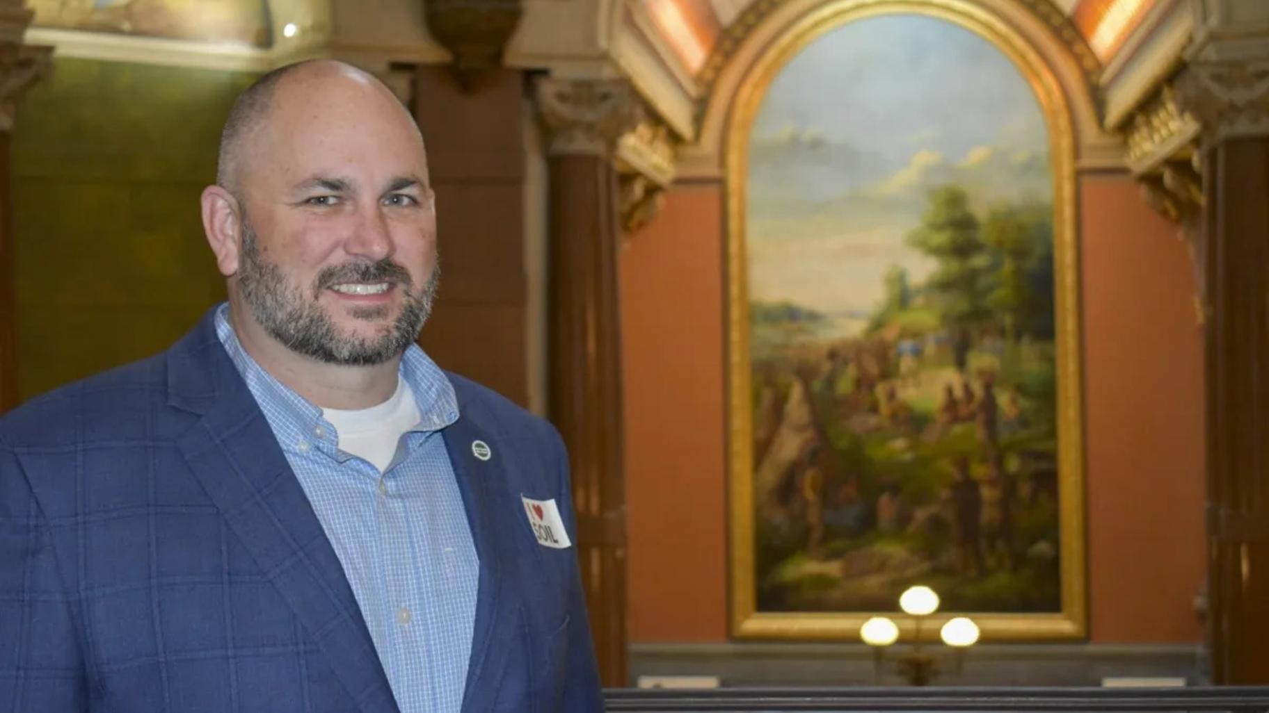 Kristopher Reynolds, Midwest Director for American Farmland Trust and a fifth-generation farmer in Nokomis, is pictured at the Illinois State Capitol on March 12, 2025. He works with farmers and landowners on conservation cropping practices to meet the goals of Illinois’ Nutrient Loss Reduction Strategy. (Jennifer Bamberg / Investigate Midwest) Kristopher Reynolds, Midwest Director for American Farmland Trust and a fifth-generation farmer in Nokomis, is pictured at the Illinois State Capitol on March 12, 2025. He works with farmers and landowners on conservation cropping practices to meet the goals of Illinois’ Nutrient Loss Reduction Strategy. (Jennifer Bamberg / Investigate Midwest)