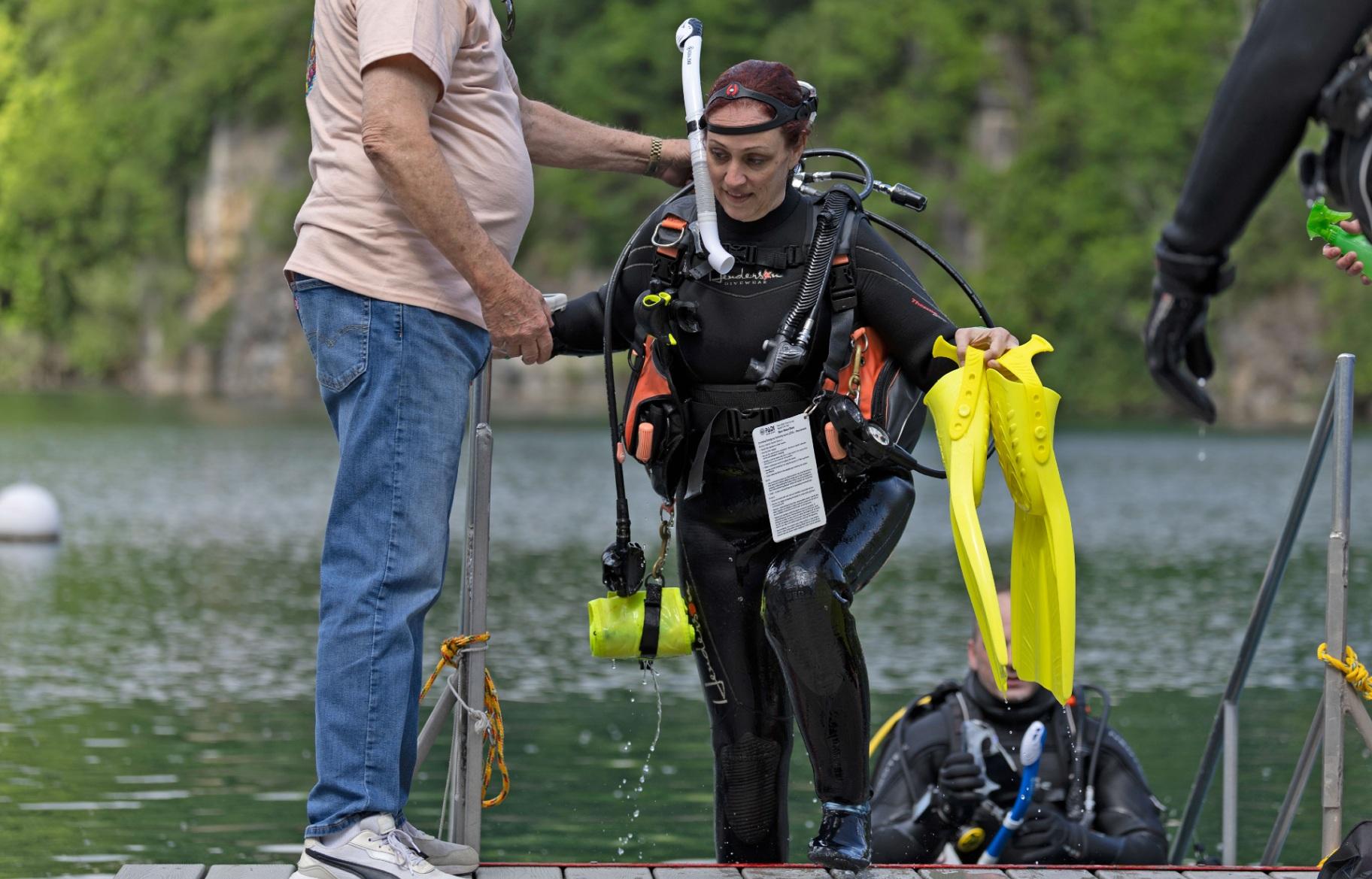 A Great American Diver employee helps owner Heather Kiswani up the stairs after a dive event April 25, 2026, at Mermet Springs in Belknap, Illinois. (Peyton Cook / Saluki Local Reporting Lab)