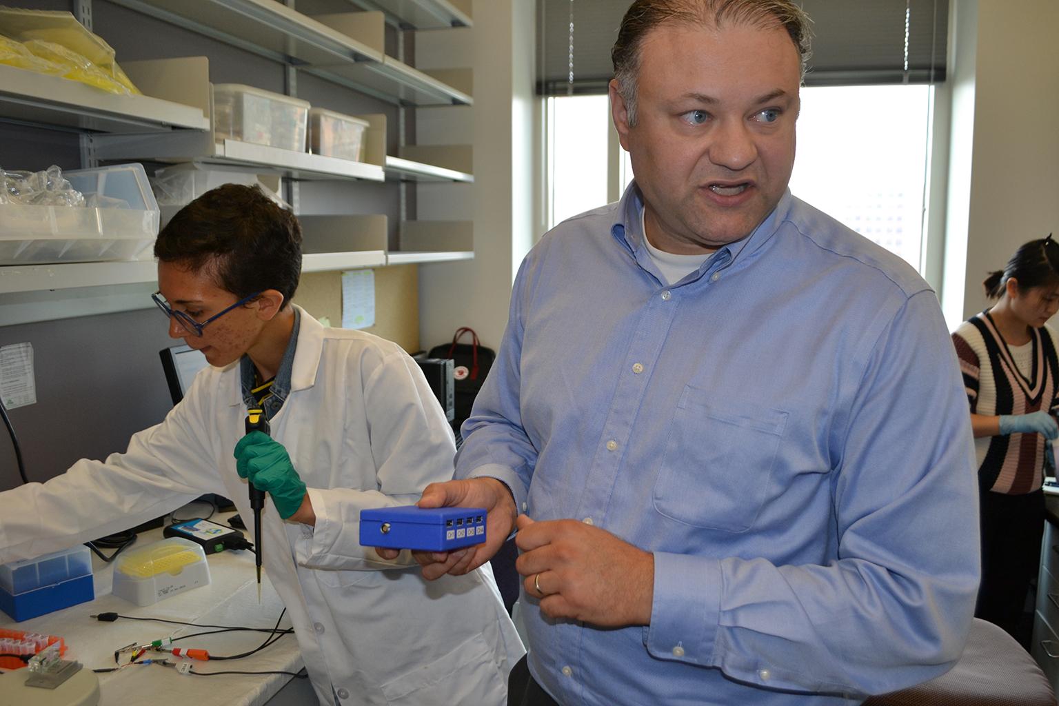 UIC bioengineering professor Ian Papautsky holds an electronic instrument used in conjunction with the sensor he is developing that will measure human exposure to toxic metals using a single finger prick of blood. (Alex Ruppenthal / Chicago Tonight)