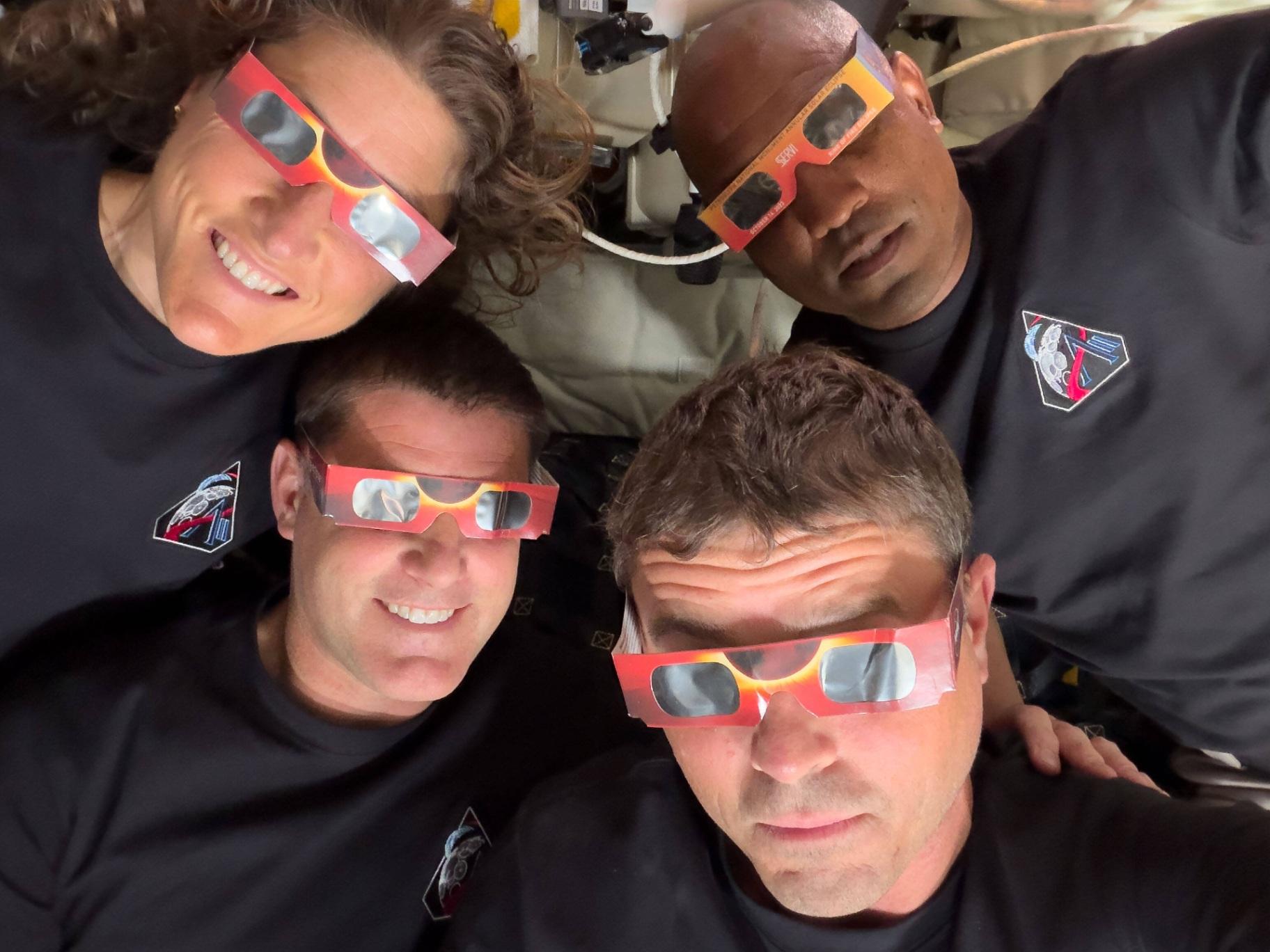 In this image provided by NASA, the Artemis II crew, counterclockwise from top left, Mission Specialist Christina Koch, Mission Specialist Jeremy Hansen, Commander Reid Wiseman, and Pilot Victor Glover pose with eclipse viewers during a lunar flyby, Monday, April 6, 2026. (NASA via AP)