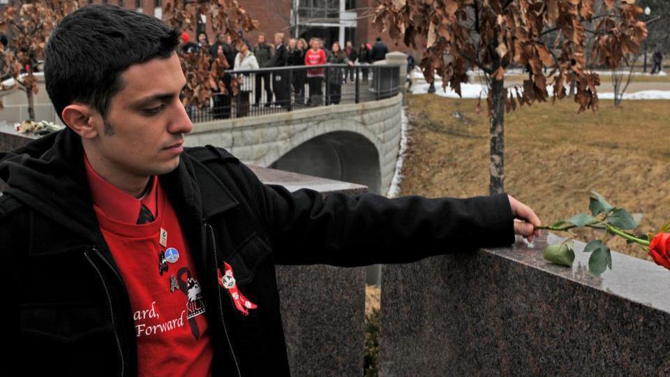 Patrick Korellis places a rose on the memorial at Northern Illinois University. (Courtesy of Patrick Korellis)