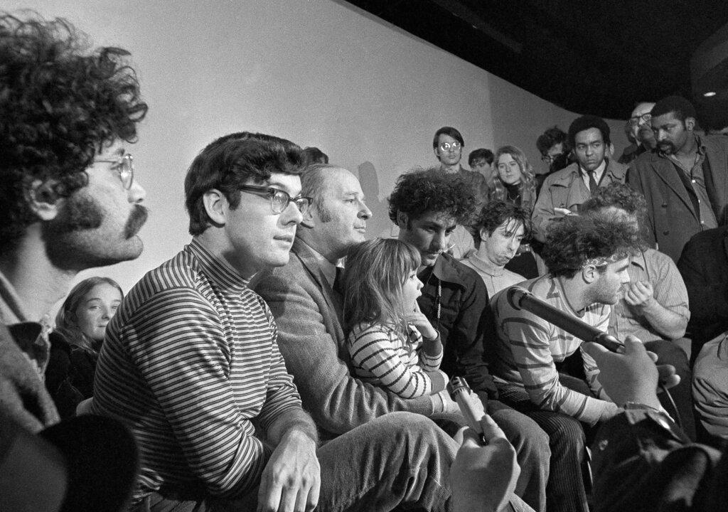 In this Feb. 28, 1970, file photo, the seven defendants in the Chicago Conspiracy Trial hold a press conference in Chicago after the 7th Circuit U.S. Court of Appeals granted their request for bail. Left to right, Lee Weiner, Rennie Davis, David Dellinger, Abbie Hoffman, Tom Hayden, (behind Hoffman), Jerry Rubin and John Froiners. Dellinger holds his granddaughter, Michelle Burd. (AP Photo / JLP, File)