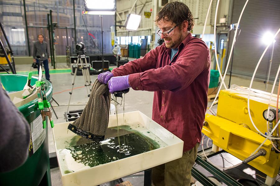 Argonne postdoctoral researcher Ed Barry wrings out a sheet of Oleo Sponge during tests at Argonne. (Mark Lopez / Argonne National Laboratory)