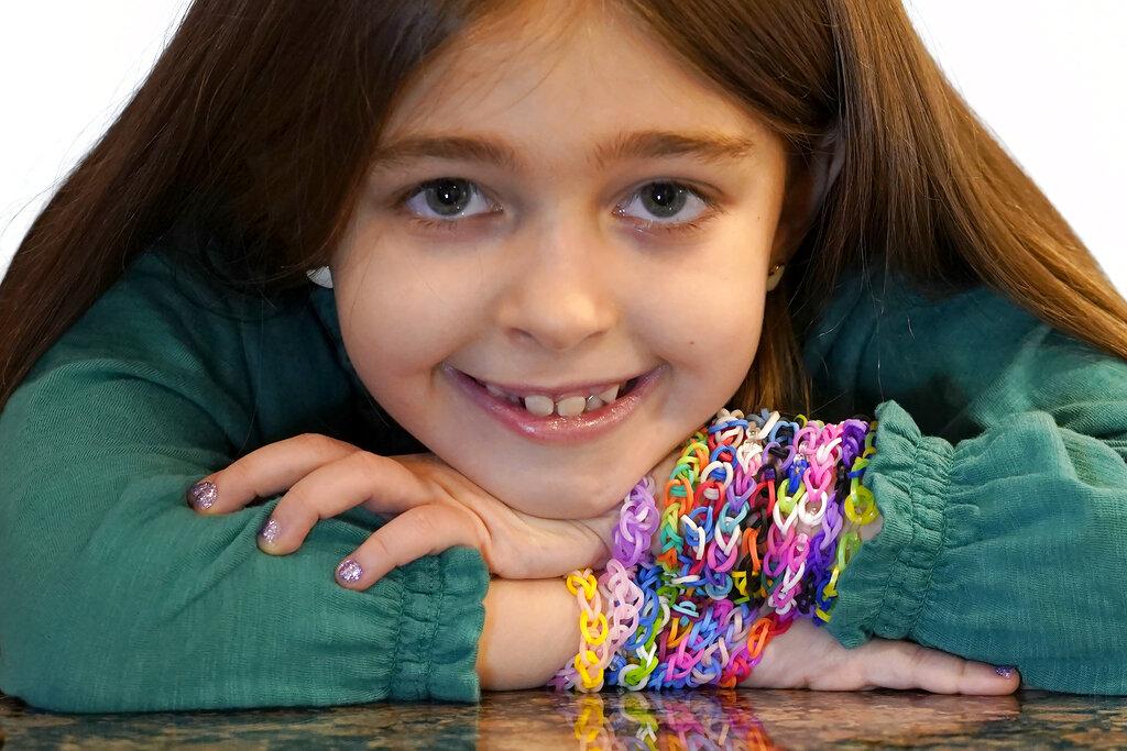 Hayley Orlinsky poses for a portrait Wednesday, Dec. 2, 2020, with several colorful rubber band bracelets she makes in her Chicago home. (AP Photo / Charles Rex Arbogast)