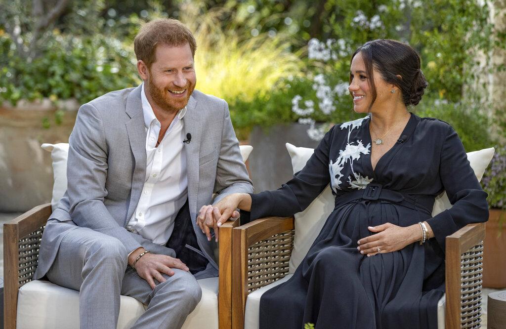 This image provided by Harpo Productions shows Prince Harry, left, and Meghan, Duchess of Sussex, speaking about expecting their second child during an interview with Oprah Winfrey. (Joe Pugliese / Harpo Productions via AP)