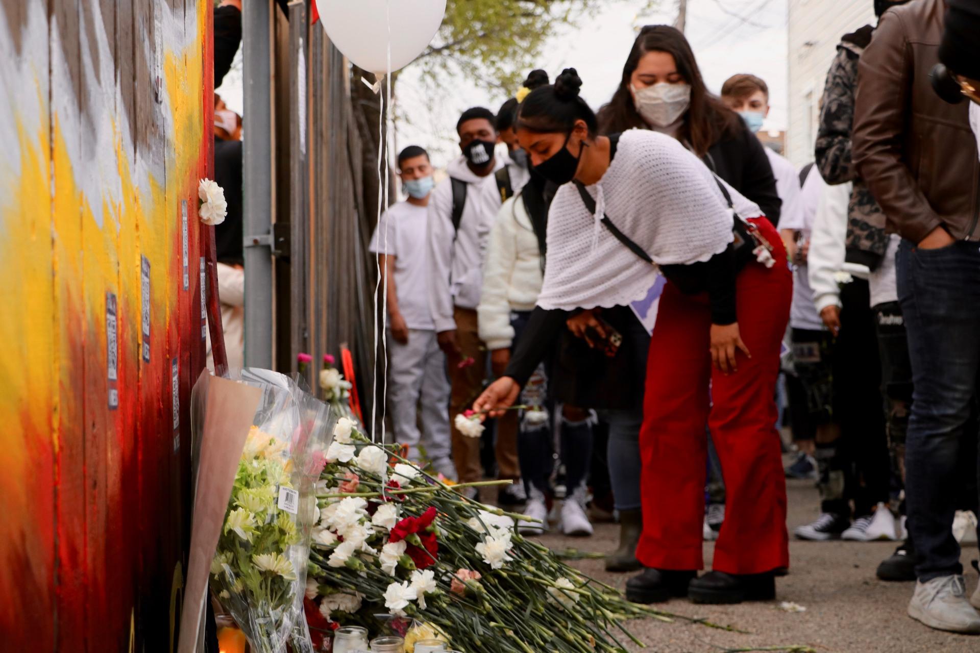 An attendee of the April 18, 2021 peace walk lays a flower at a memorial for 13-year-old Adam Toledo in Chicago’s Little Village neighborhood. Toledo was fatally shot by a police officer in this location on March 29, 2021. (Evan Garcia / WTTW News)
