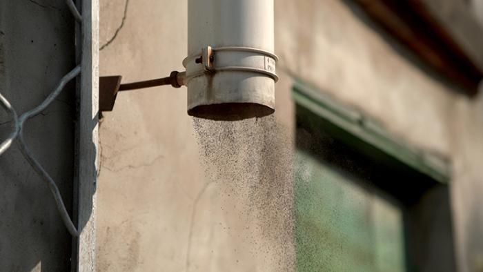 A production still from "I Can Only See Shadows," showing black dust exiting a pipe on Chicago’s Southeast Side. (Marissa Lee Benedict, David Rueter / Courtesy of Museum of Contemporary Photography)