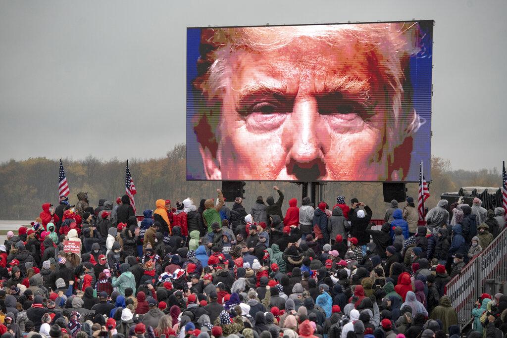 Supporters of President Donald Trump watch a video screen showing his face during a campaign event on Tuesday, Oct. 27, 2020, in Lansing, Mich. (Nicole Hester / Mlive.com - Ann Arbor News via AP)