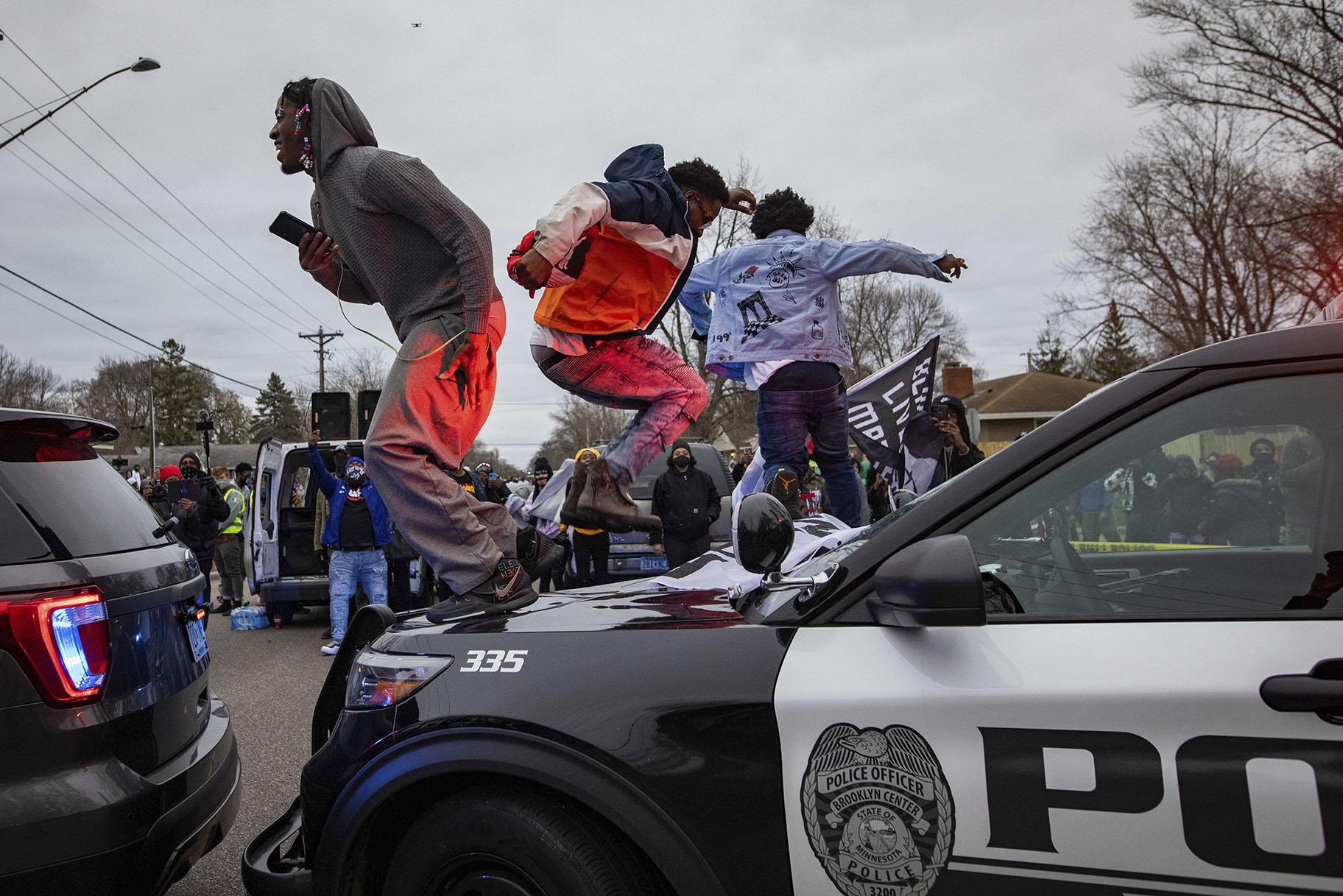 Men jump on the hood of a police car after a family said a man was shot and killed by law enforcement on Sunday, April 11, 2021, in Brooklyn Center, Minn. (AP Photo / Christian Monterrosa)