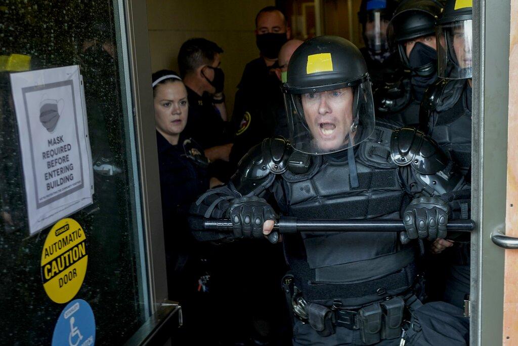 Police try to secure the public safety building from protesters Monday, Aug. 24, 2020, in Kenosha, Wis. (AP Photo / Morry Gash)