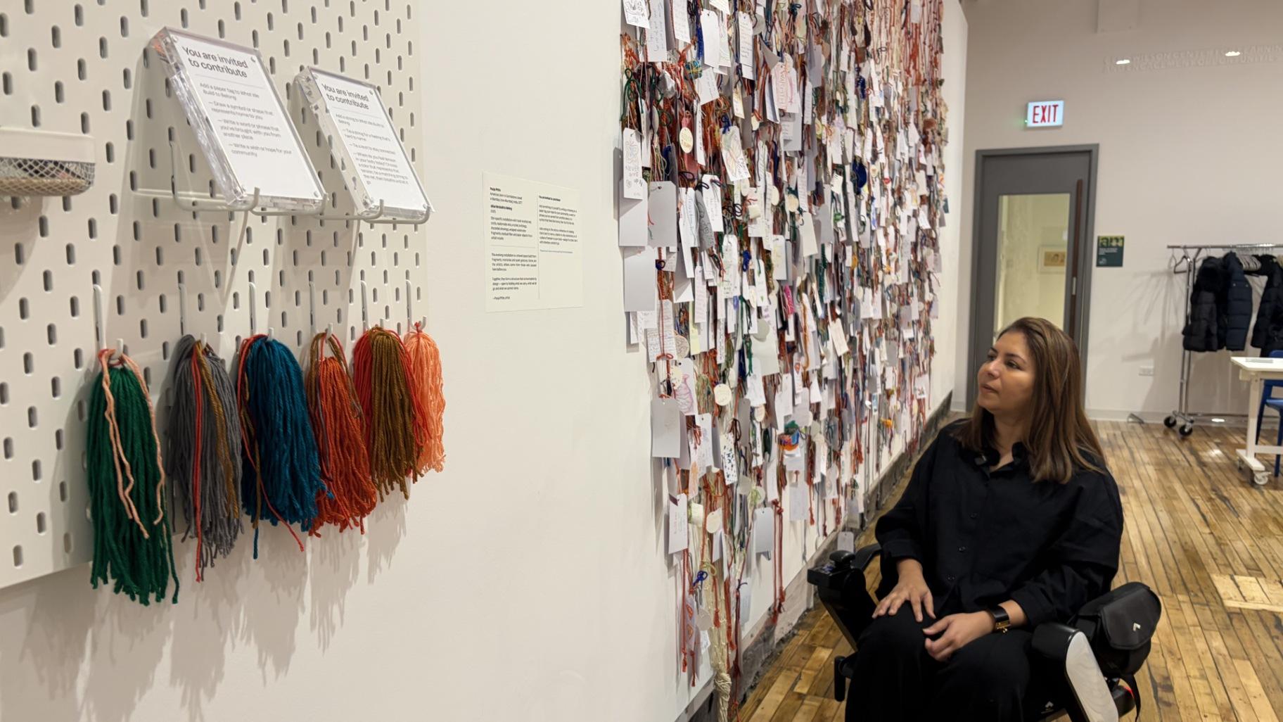 Artist Pooja Pittie views her artwork, “What We Build to Belong,” on Dec. 17, 2025, at the Intuit Art Museum, 756 N. Milwaukee Ave., in West Town. The interactive piece has more than 500 personalized tags added by visitors, according to the museum. (Eunice Alpasan / WTTW News)