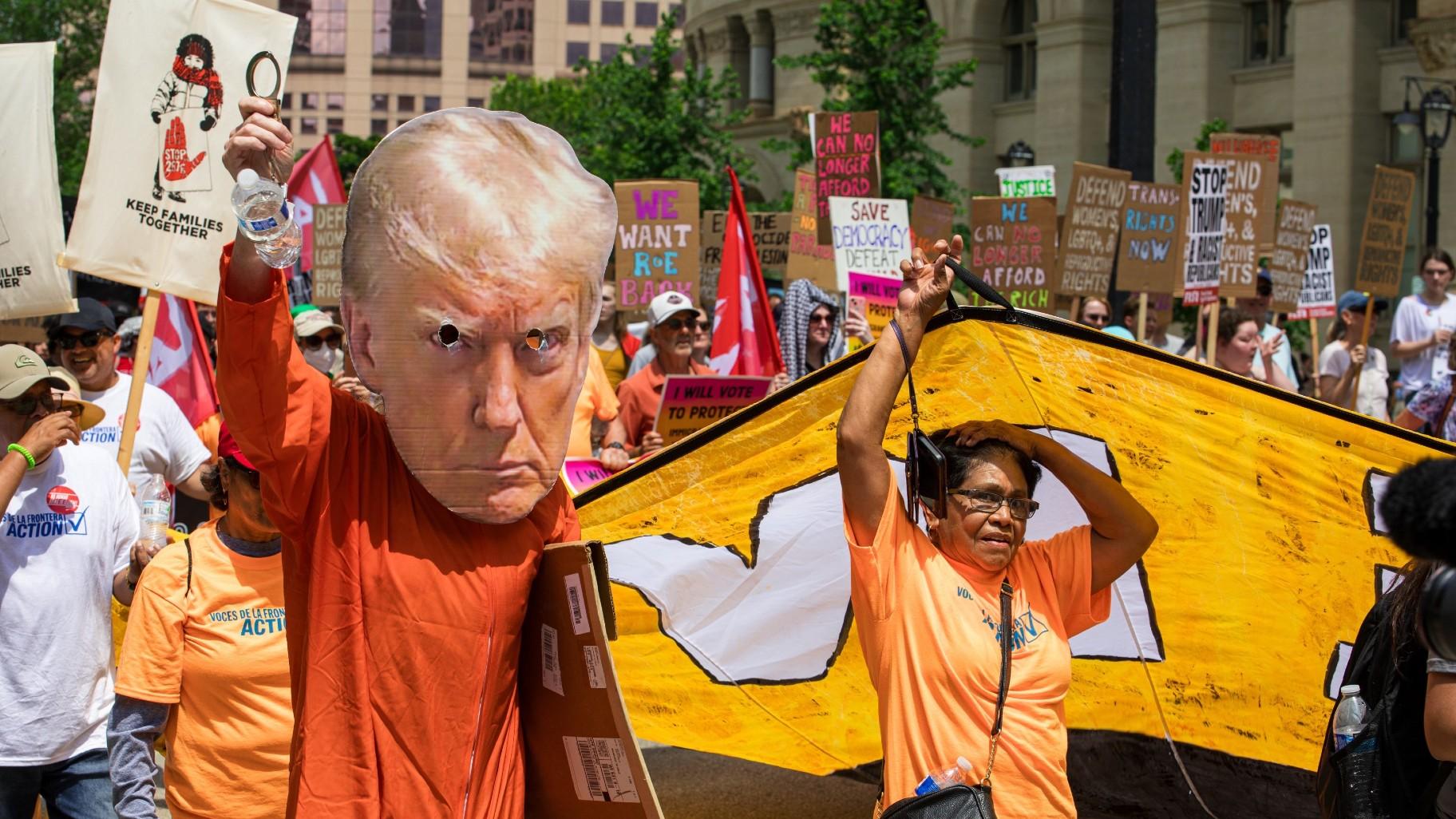 A person walks in the march wearing a giant poster head of former President Donald Trump, while wearing an orange jumpsuit on Monday, July 15, 2024. (Michael Izquierdo / WTTW News)