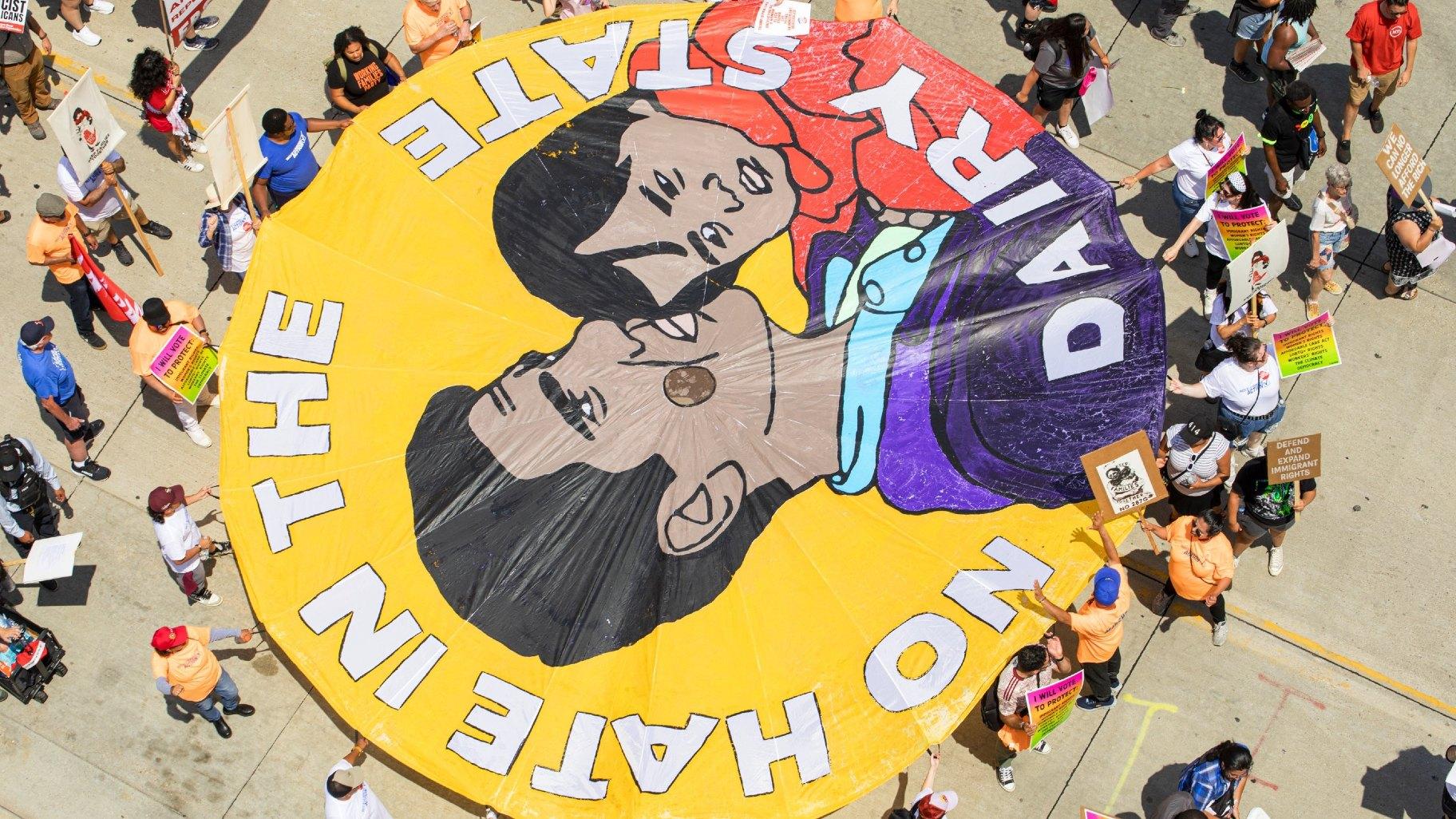A tarp held by protesters reads “No Hate in the Dairy State” during the march on Monday, July 15, 2024. (Michael Izquierdo / WTTW News)