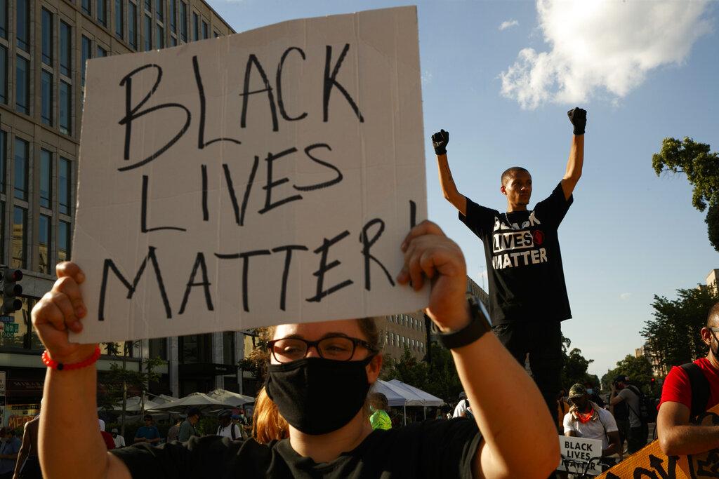 In this June 24, 2020, file photo, Antonio Mingo, right, holds his fists in the air as demonstrators protest in front of a police line on a section of 16th Street that’s been renamed Black Lives Matter Plaza, in Washington. (AP Photo / Jacquelyn Martin, File)