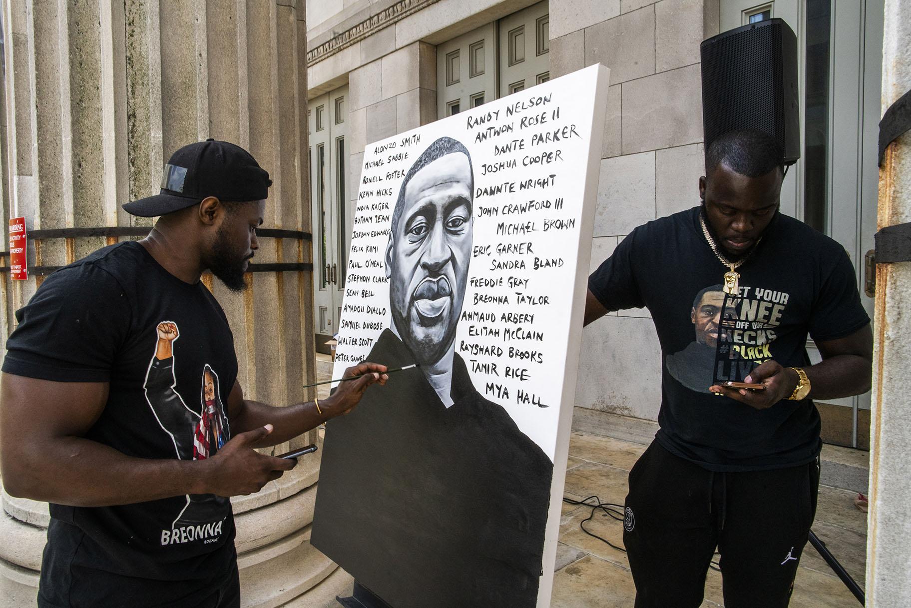 Artist Dennis Owes, 31, from Ghana gives the last touch to his portrait of George Floyd during a rally on Sunday, May 23, 2021, in Brooklyn borough of New York. (AP Photo / Eduardo Munoz Alvarez)