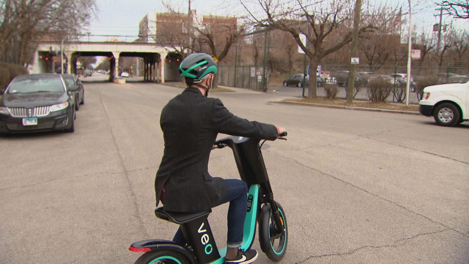 “Chicago Tonight” producer Nick Blumberg tests a seated electric scooter. (WTTW News)