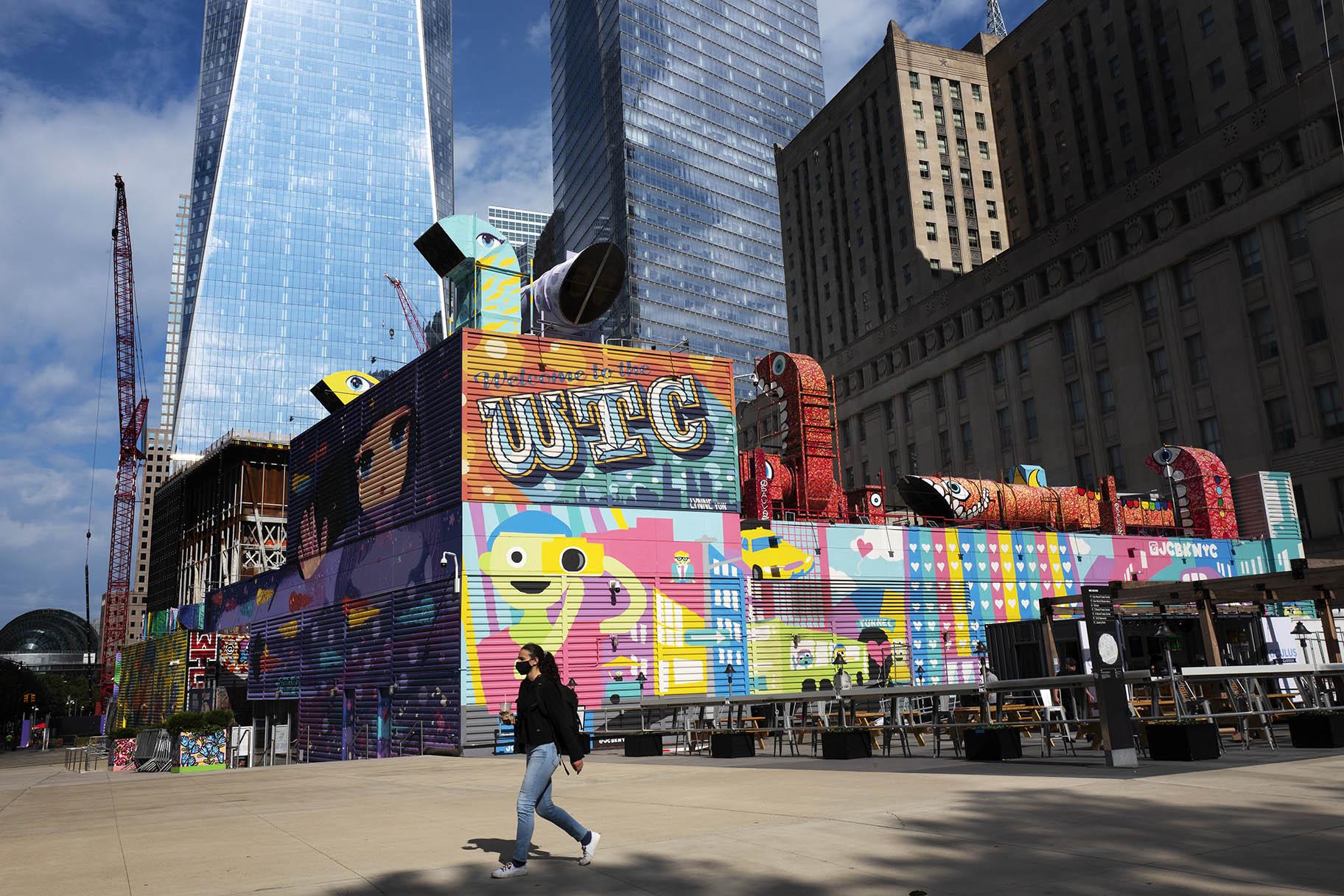 A woman walks by the colorful murals that surround the foundation for 2 World Trade Center, Wednesday, Sept. 8, 2021 in New York. (AP Photo / Mark Lennihan)