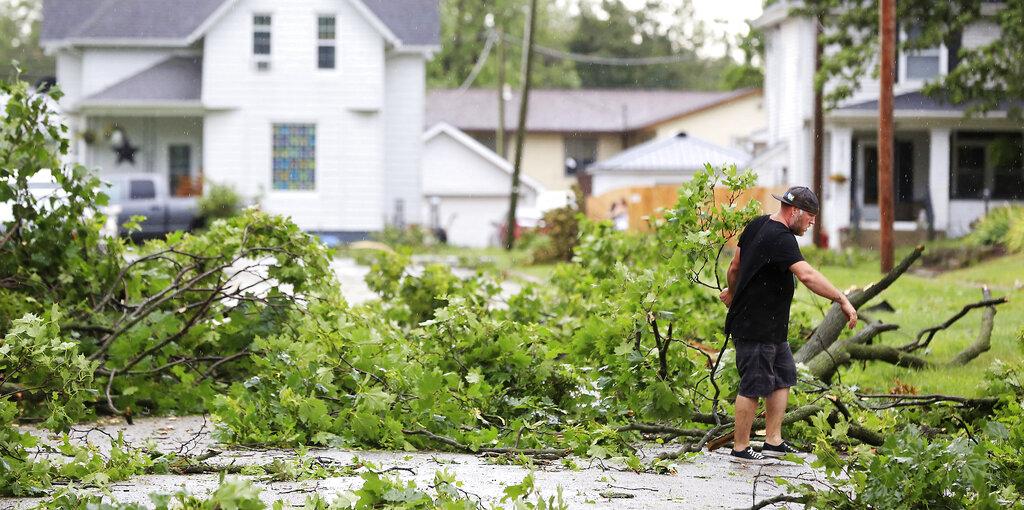 Seth James clears downed tree limbs in front of his home in Walcott after high winds and heavy rain passed through the area Monday, Aug. 10, 2020, in Davenport, Iowa. (Kevin E. Schmidt / Quad City Times via AP)