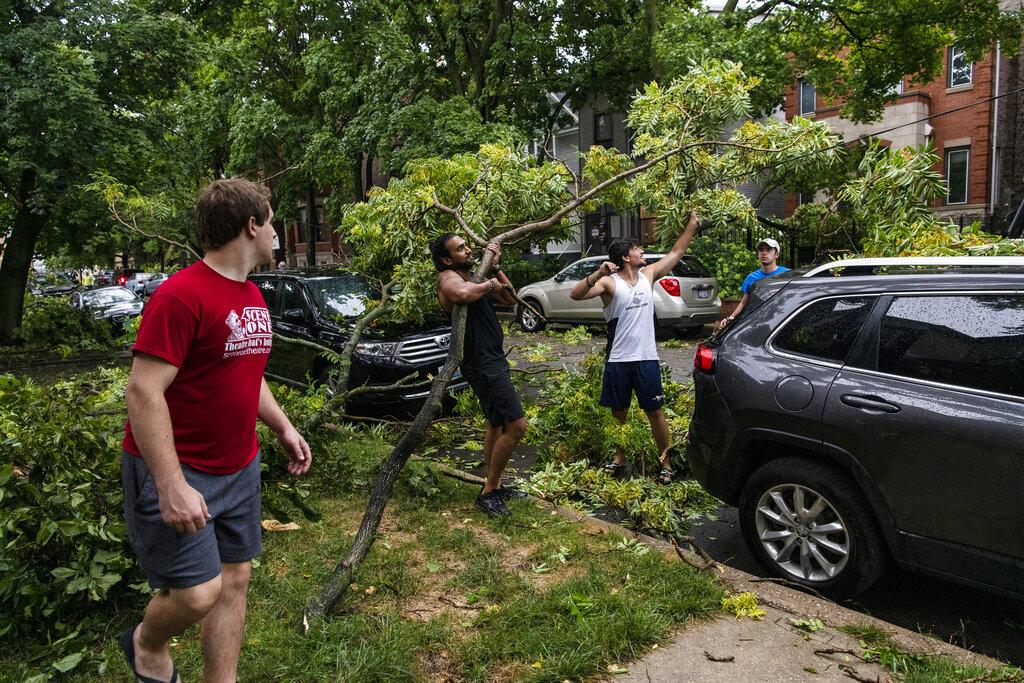 Residents remove a tree branch from a car and a downed power line after a severe storm moved through Chicago, Monday, Aug. 10, 2020. (Tyler LaRiviere / Chicago Sun-Times via AP)