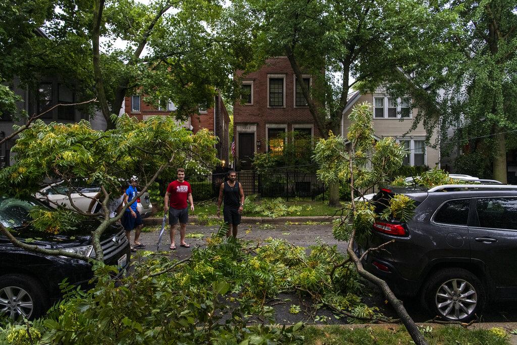 A group of neighbors surveys the damage to vehicles on their block after a severe thunderstorm battered Chicago neighborhoods, Monday, Aug. 10, 2020. (Tyler LaRiviere / Sun-Times / Chicago Sun-Times via AP)