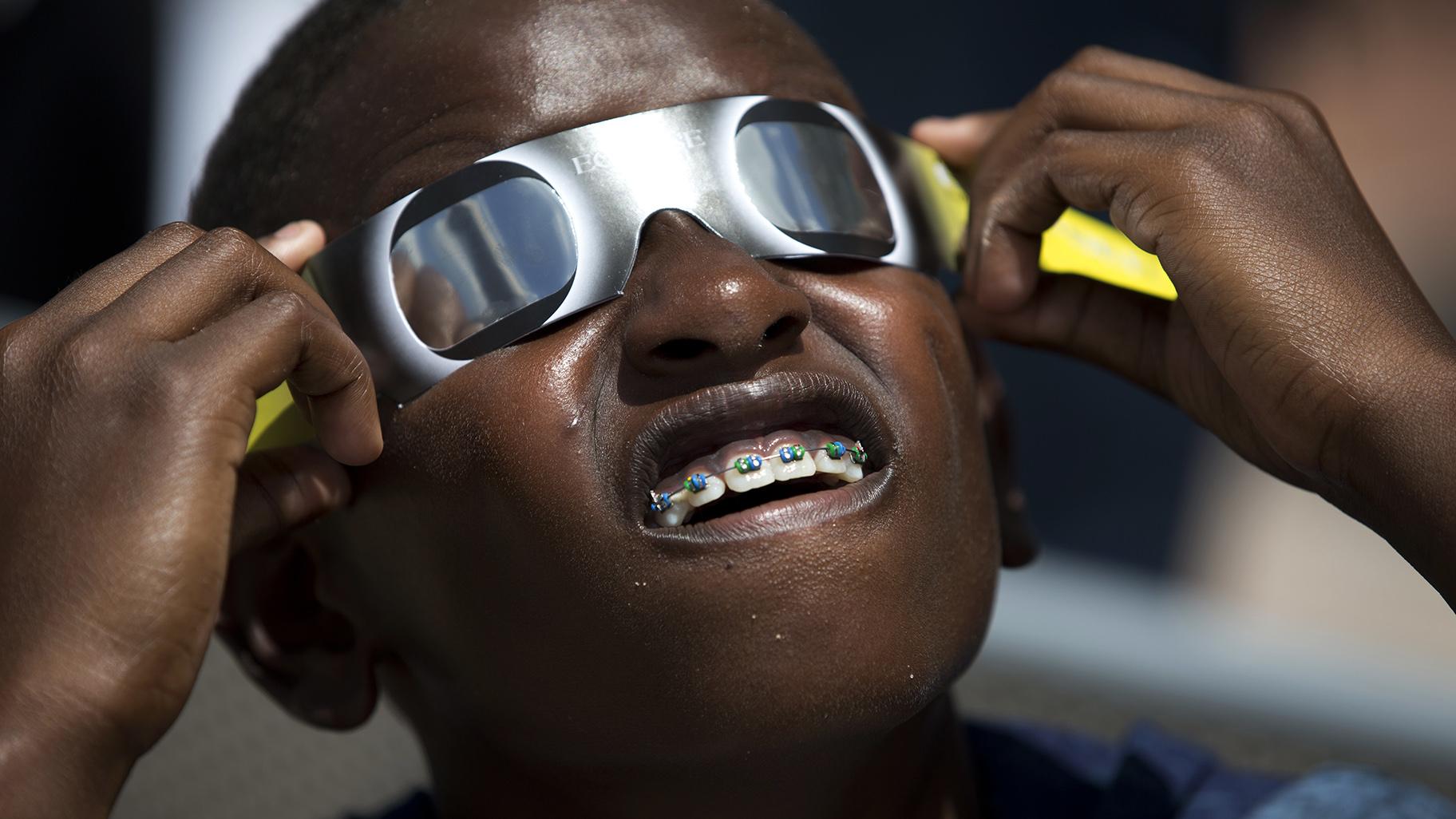 Blake Davis, 10, of Coral Springs, Fla., looks through solar glasses as he watches the eclipse, Monday, Aug. 21, 2017, at Nova Southeastern University in Davie, Fla. (AP Photo / Wilfredo Lee, File)