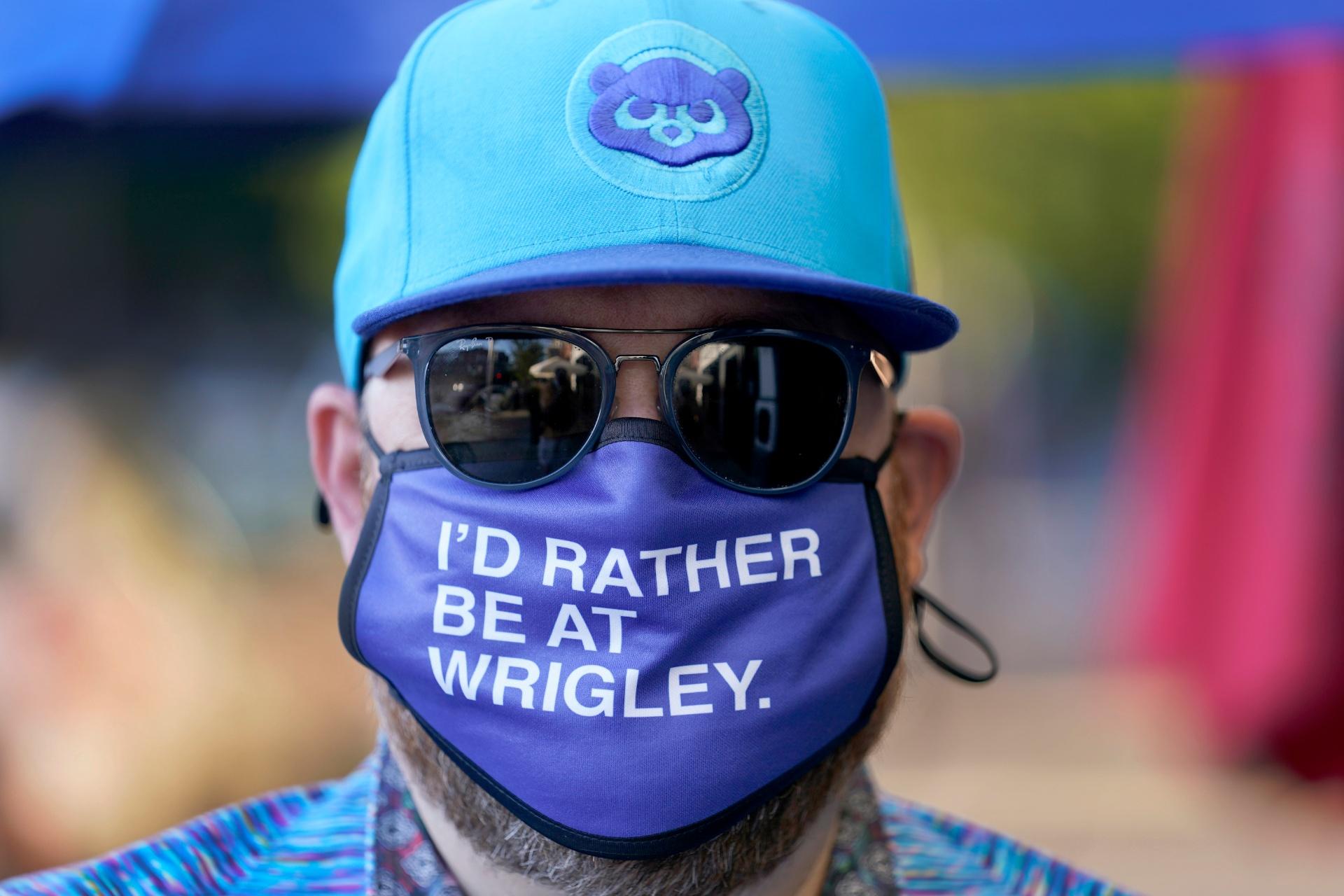Patrick McCarron wears a Chicago Cubs cap and protective mask Friday, Sept. 4, 2020, as he heads to a rooftop venue to watch the Cubs host the rival St. Louis Cardinals at Wrigley Field in Chicago. (AP Photo / Charles Rex Arbogast)