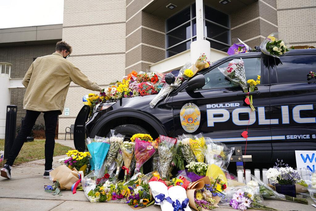 A man leaves a bouquet on a police cruiser parked outside the Boulder Police Department after an officer was one of the victims of a mass shooting at a King Soopers grocery store Tuesday, March 23, 2021, in Boulder, Colo. (AP Photo / David Zalubowski)