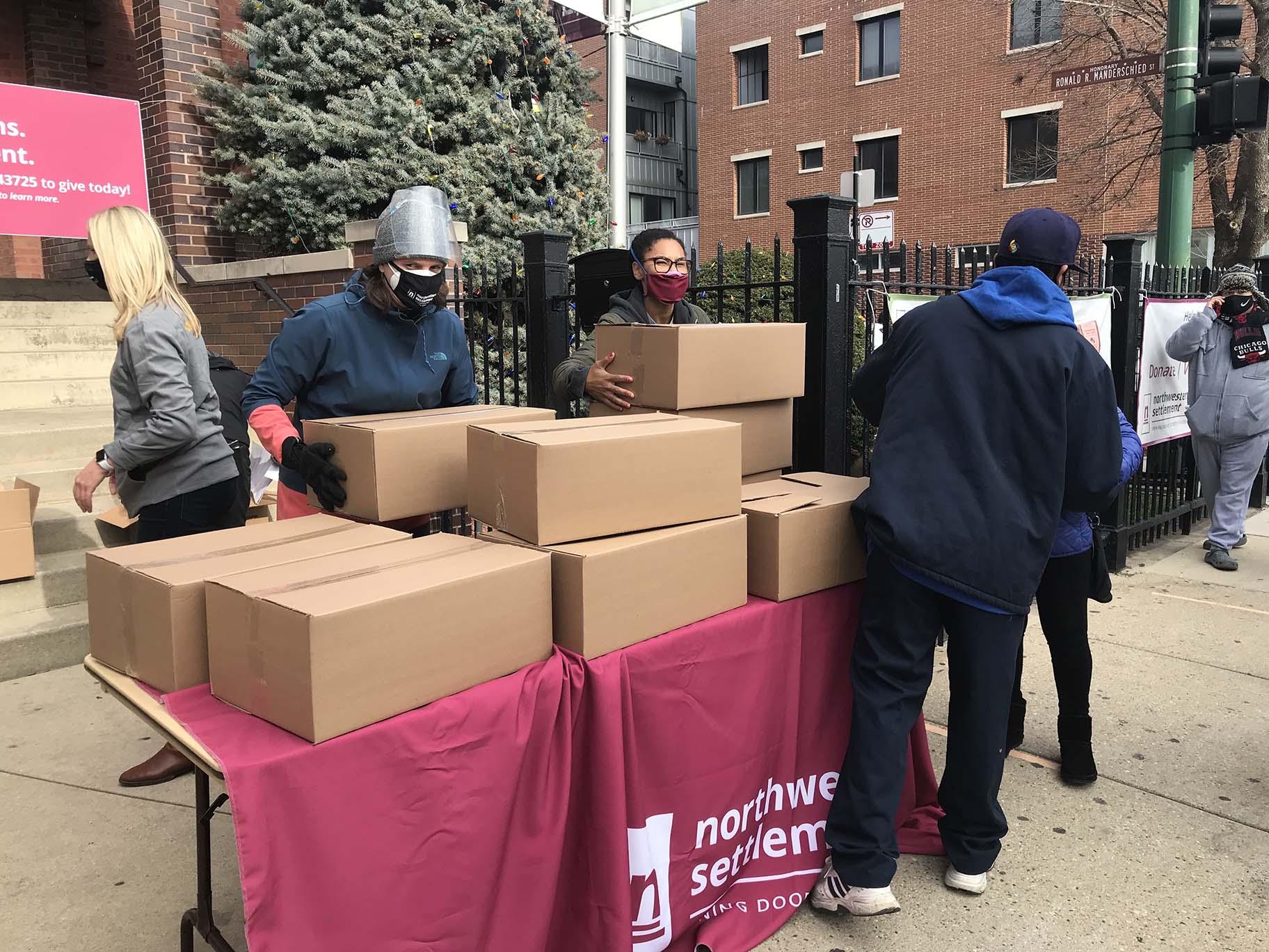 Volunteers help distribute meals to families and at Northwestern Settlement in West Town. (Ariel Parrella-Aureli / WTTW News) 