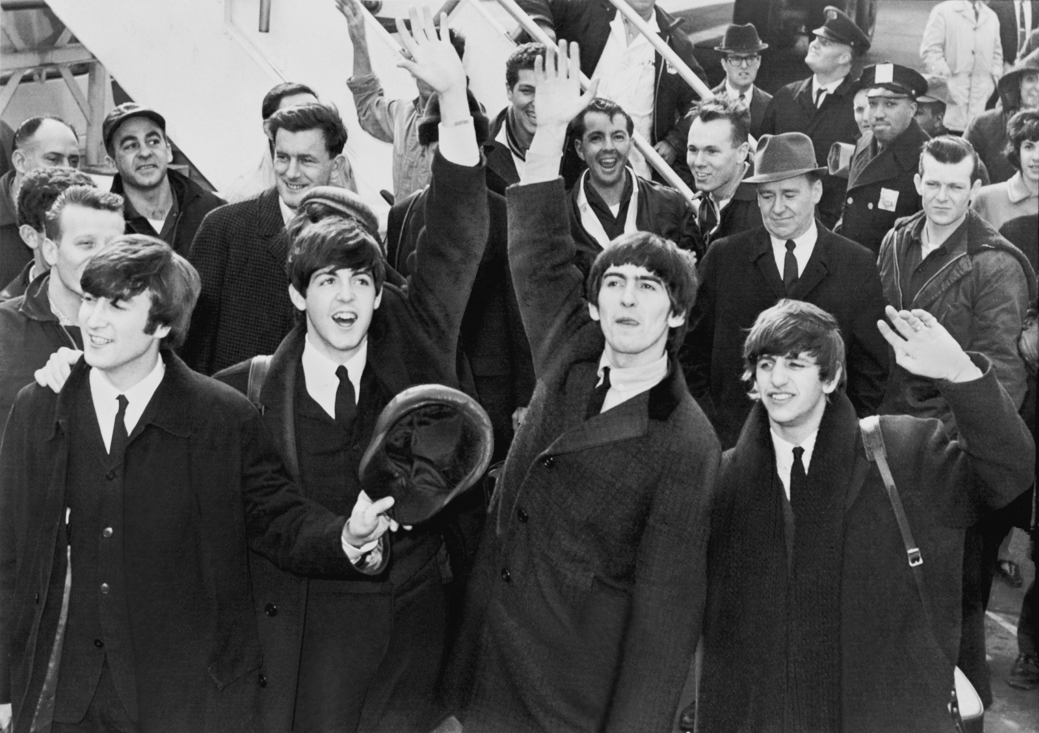 The Beatles wave to fans after arriving at Kennedy Airport in February 1964. 