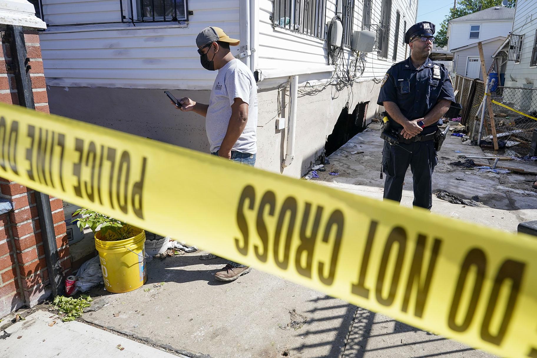 A police officer stands guard as a man survey the damage to home where people died after their basement apartment flooded in the Jamaica neighborhood of the Queens borough of New York, Thursday, Sept. 2, 2021, in New York. (AP Photo / Mary Altaffer)
