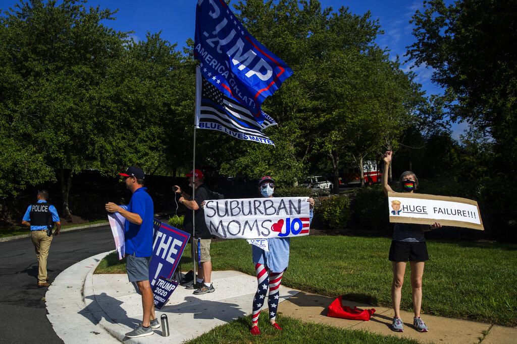 Protesters and supporters of President Donald Trump wave banners as the president's motorcade enters the Trump National Golf Club in Sterling, Va., Sunday, Aug. 23, 2020. (AP Photo / Manuel Balce Ceneta)