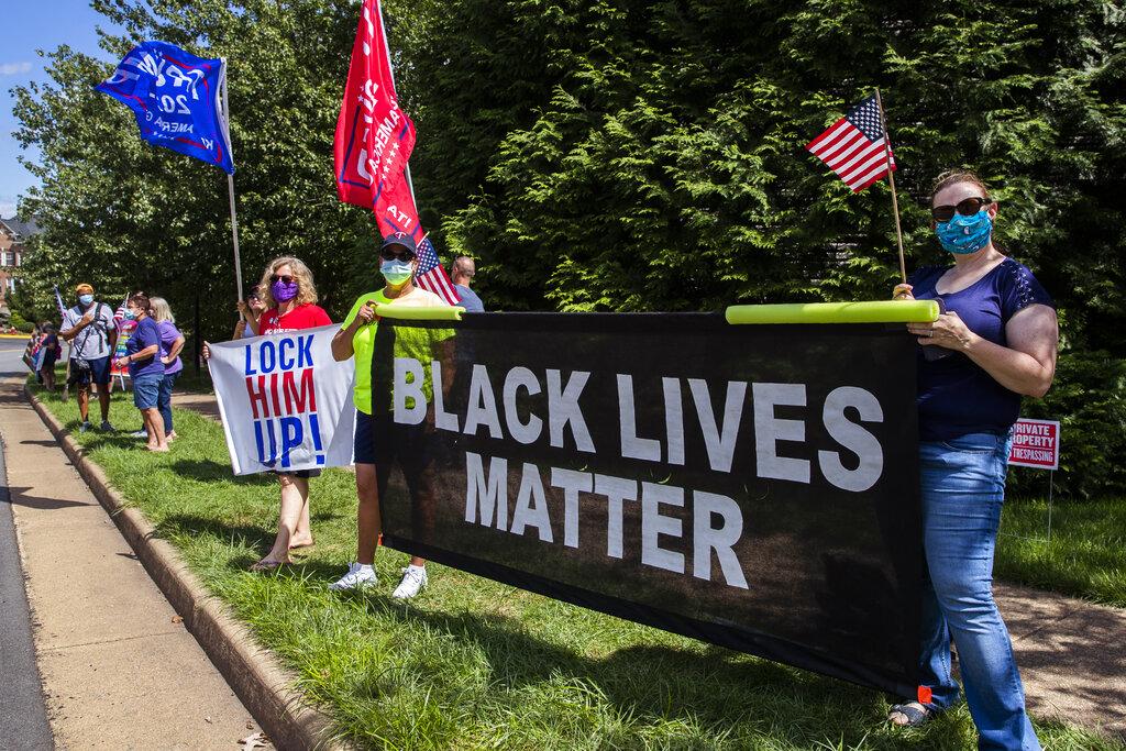 Supporters of President Donald Trump and protesters hold banners as they wait for the motorcade of President Trump outside the Trump National Golf Club in Sterling, Va., Sunday, Aug. 30, 2020. (AP Photo / Manuel Balce Ceneta)