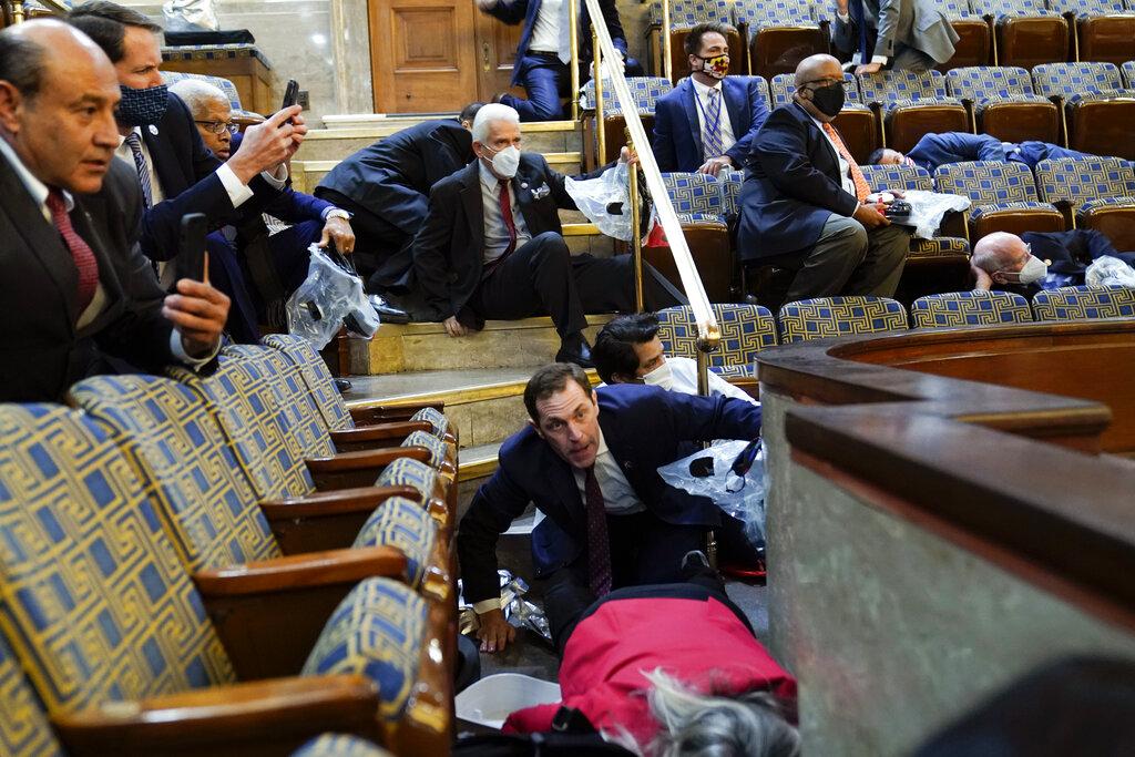 In this Jan. 6, 2021, file photo people shelter in the House gallery as rioters try to break into the House Chamber at the U.S. Capitol. (AP Photo / Andrew Harnik, File)