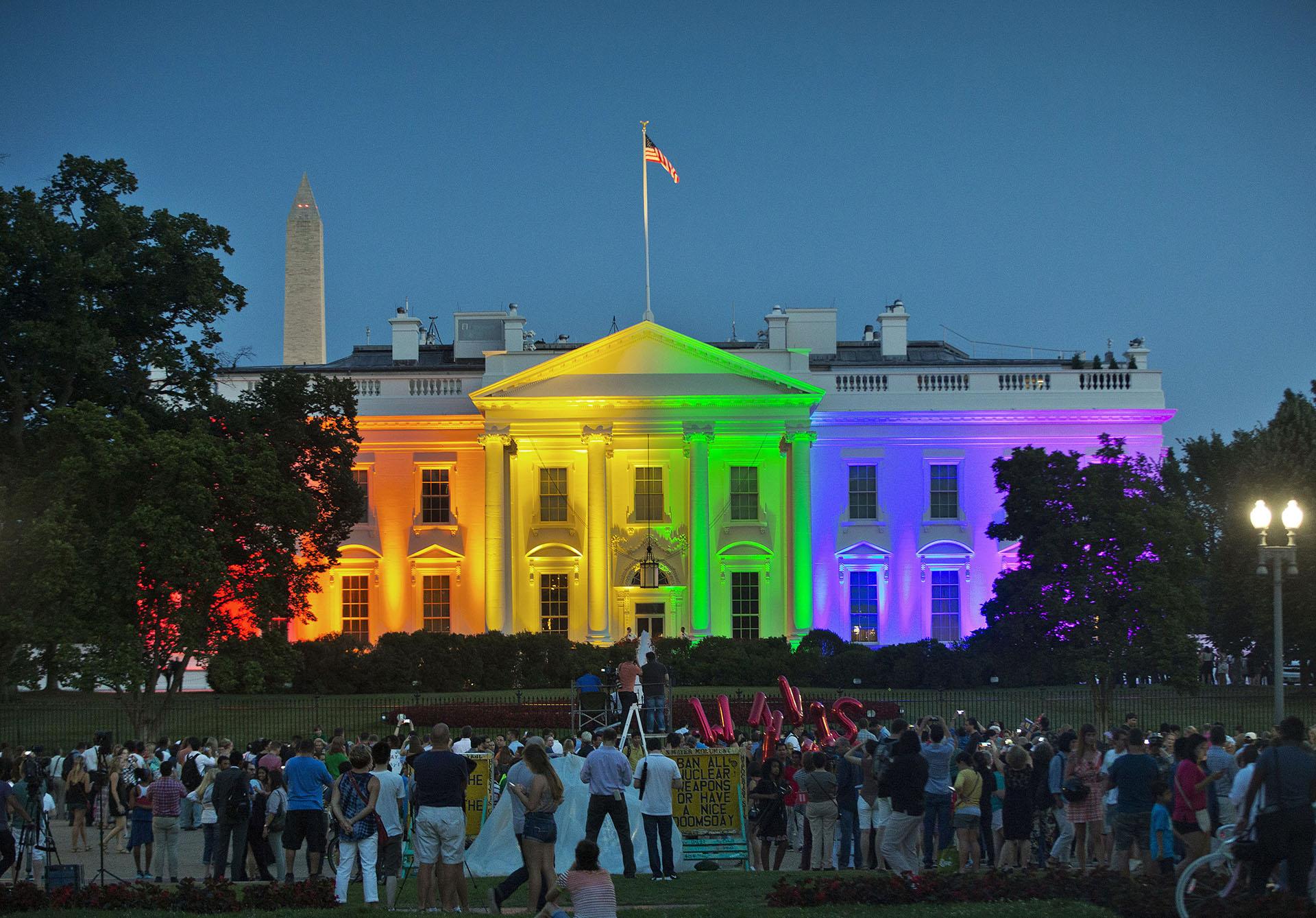 In this Friday, June 26, 2015 file photo, people gather in Lafayette Park to see the White House illuminated with rainbow colors in commemoration of the Supreme Court's ruling to legalize same-sex marriage in Washington. The Trump administration Friday, June 12, 2020, finalized a regulation that overturns Obama-era protections for transgender people against sex discrimination in health care. (AP Photo/Pablo Martinez Monsivais, File)
