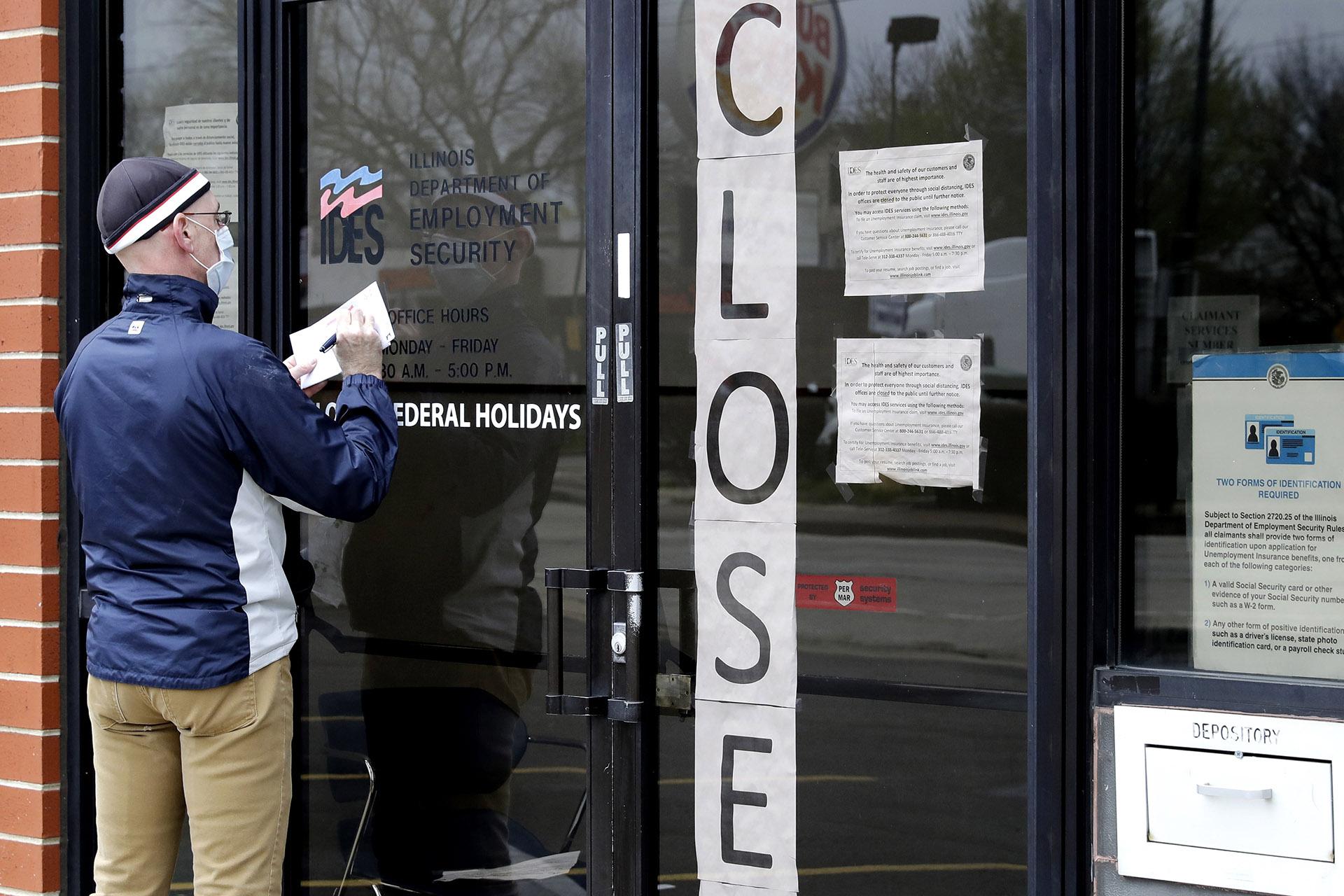 In this April 30, 2020 file photo, a man writes information in front of Illinois Department of Employment Security in Chicago. (AP Photo / Nam Y. Huh, File)