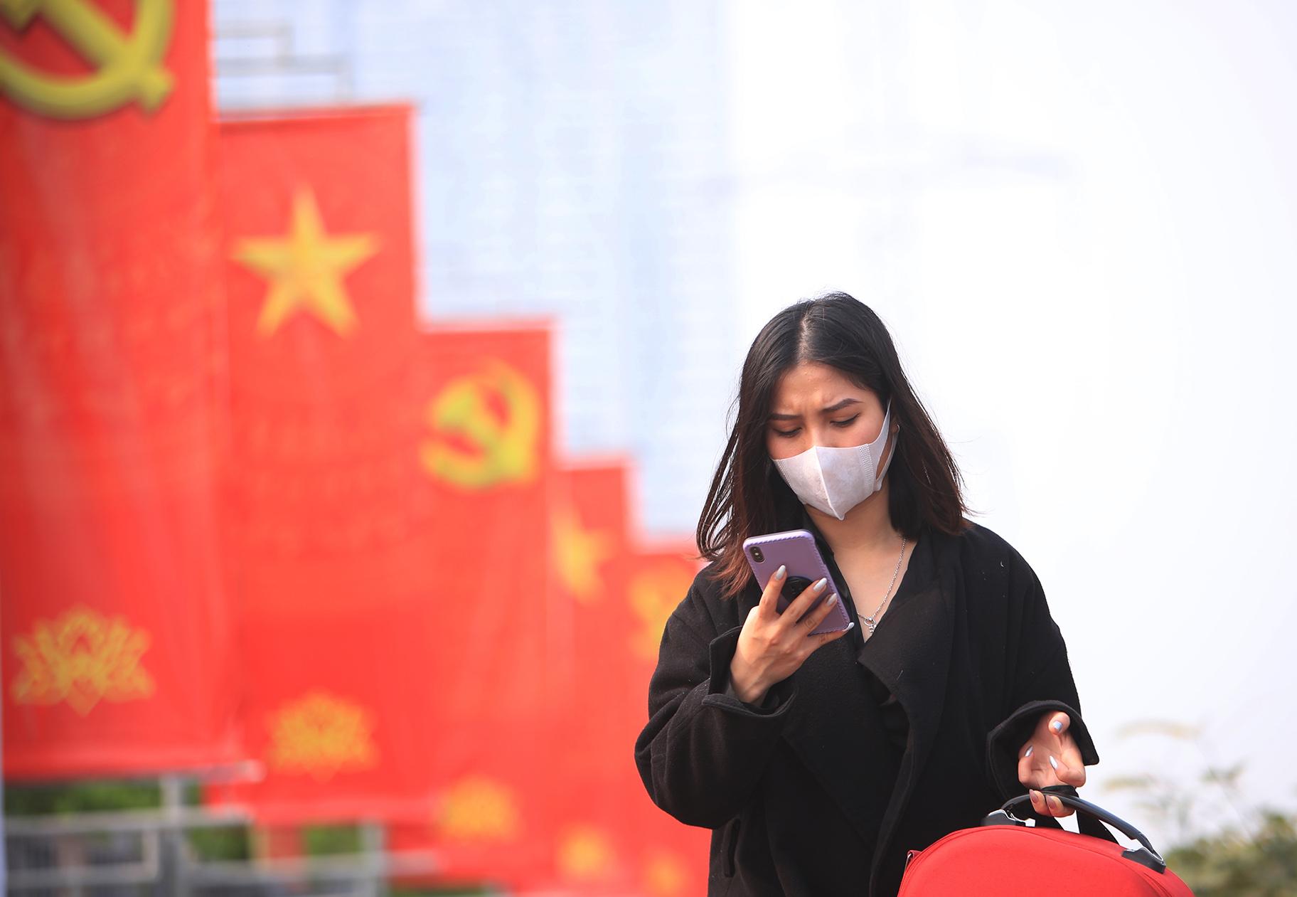 In this Jan. 23, 2021 file photo, a woman wearing face mask looks at her phone in Hanoi, Vietnam. (AP Photo / Hau Dinh, File)