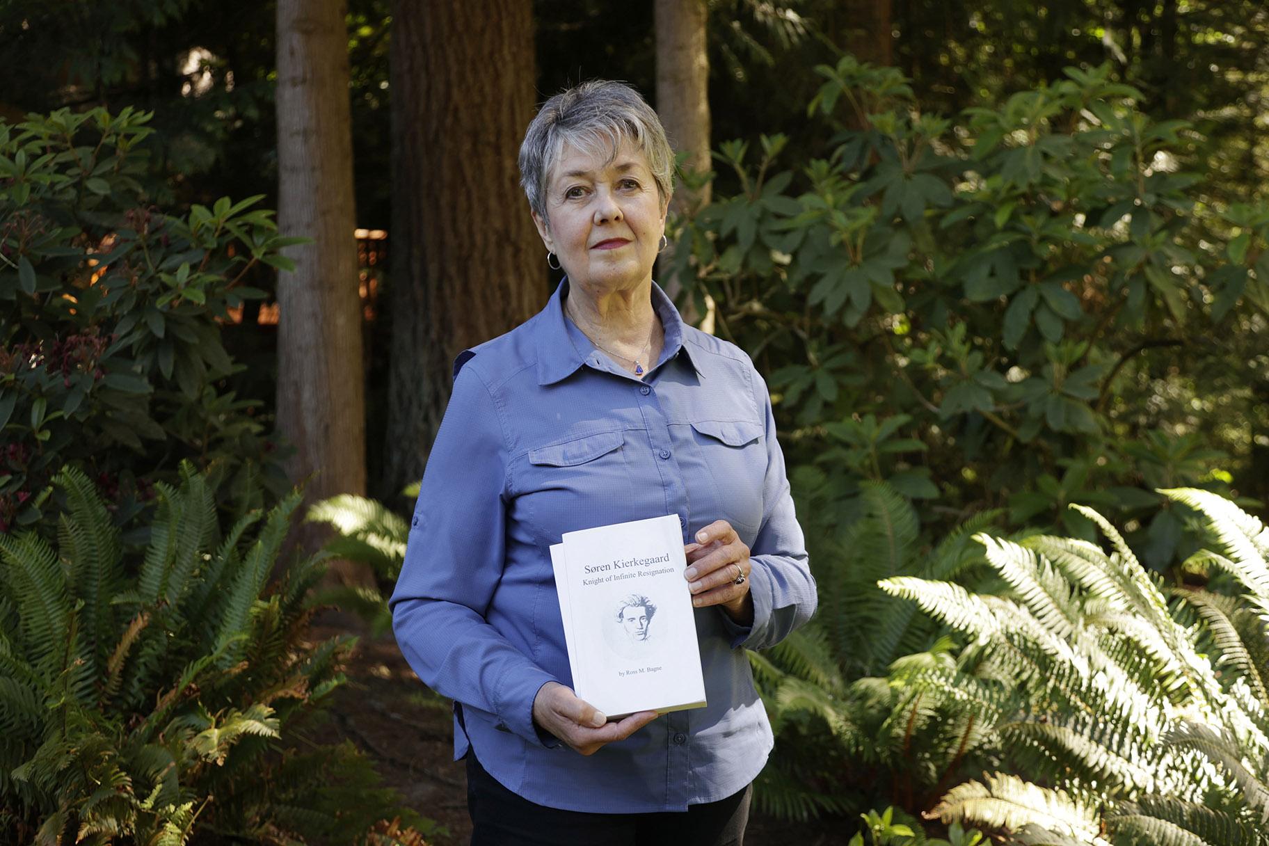 Karen McKnight stands in her backyard on Saturday, June 19, 2021, in Sammamish, Wash., holding two books written by her brother Ross Bagne of Cheyenne, Wyo. Nearly all COVID-19 deaths in the United States now are in people who weren’t vaccinated, like Bagne, a staggering demonstration of how effective the vaccines have been (AP Photo / John Froschauer)