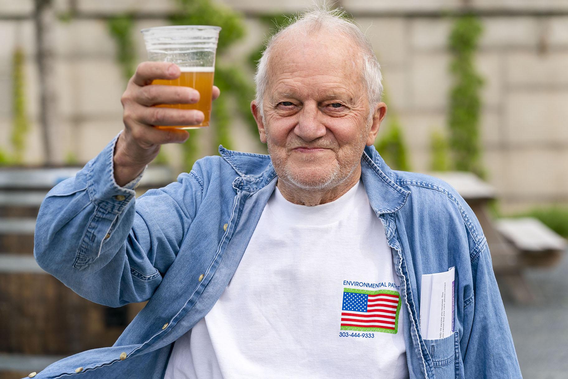 In this May 6, 2021 photo, George Ripley, 72, of Washington, holds up his free beer after receiving the J&J COVID-19 vaccine shot, at The REACH at the Kennedy Center in Washington. (AP Photo / Jacquelyn Martin)