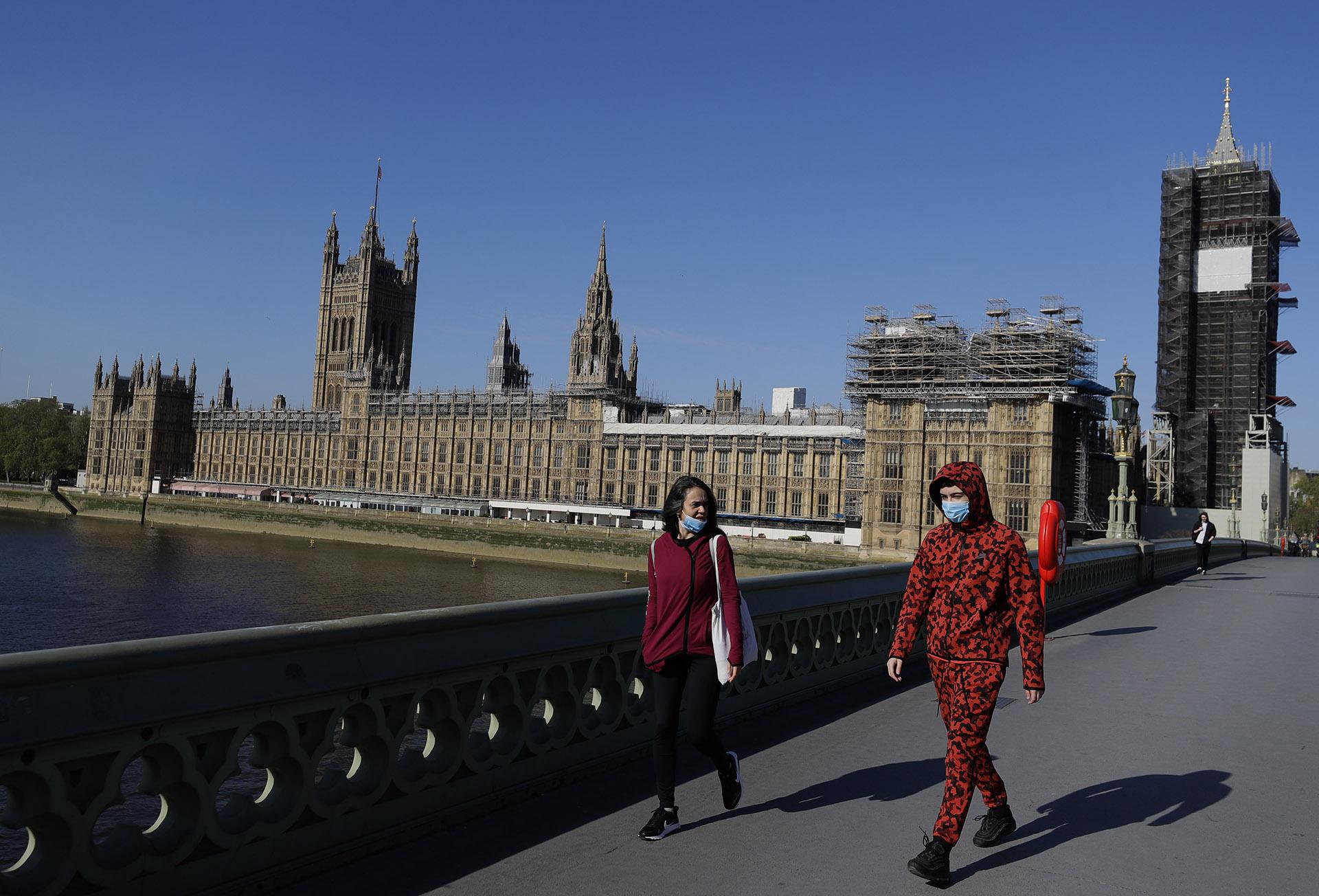 People wear masks as they walk near Britain’s Houses of Parliament as the country is in lockdown to help curb the spread of coronavirus, in London, Tuesday, April 21, 2020. AP Photo / Kirsty Wigglesworth)