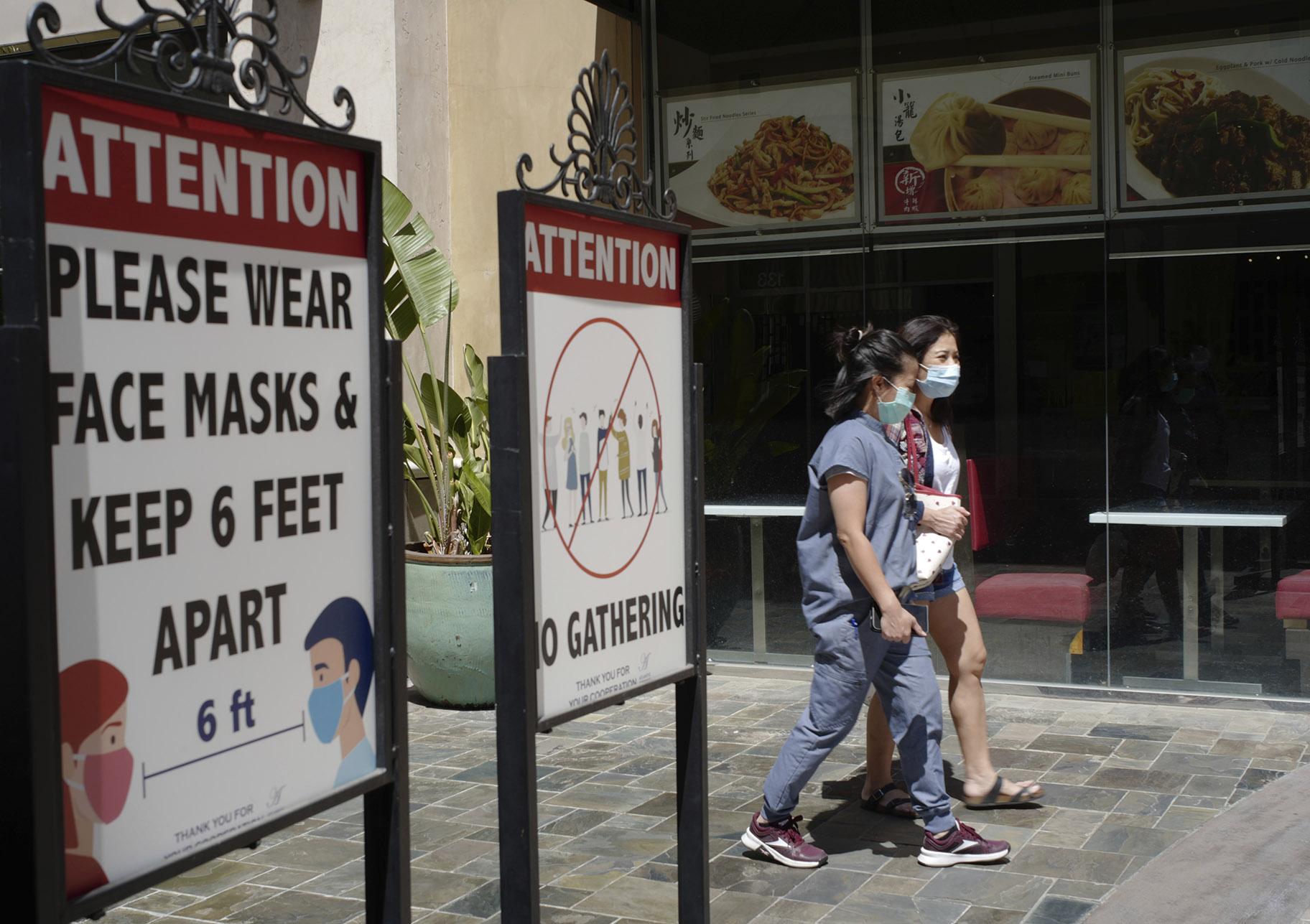 In this June 11, 2021, file photo, customers wear face masks in an outdoor mall with closed business amid the COVID-19 pandemic in Los Angeles. (AP Photo / Damian Dovarganes, File)