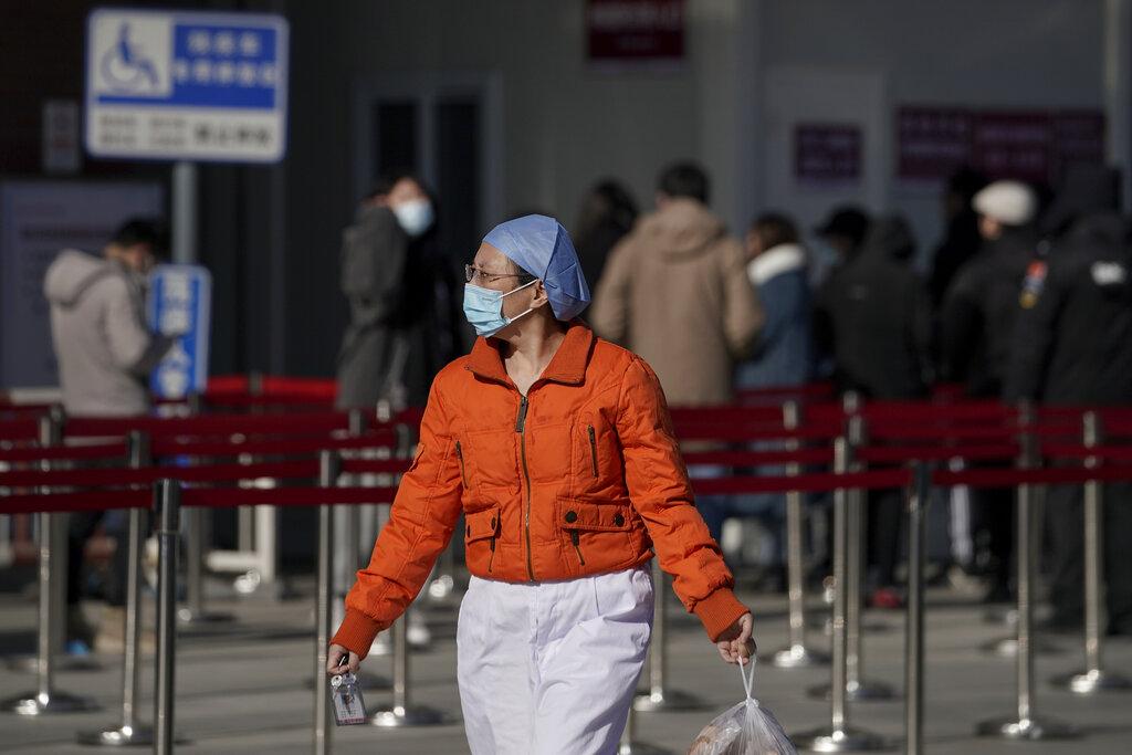 A nurse wearing a face mask to help curb the spread of the coronavirus walks by people lining up for a coronavirus test at a hospital in Beijing, Sunday, Jan. 17, 2021. (AP Photo / Andy Wong)