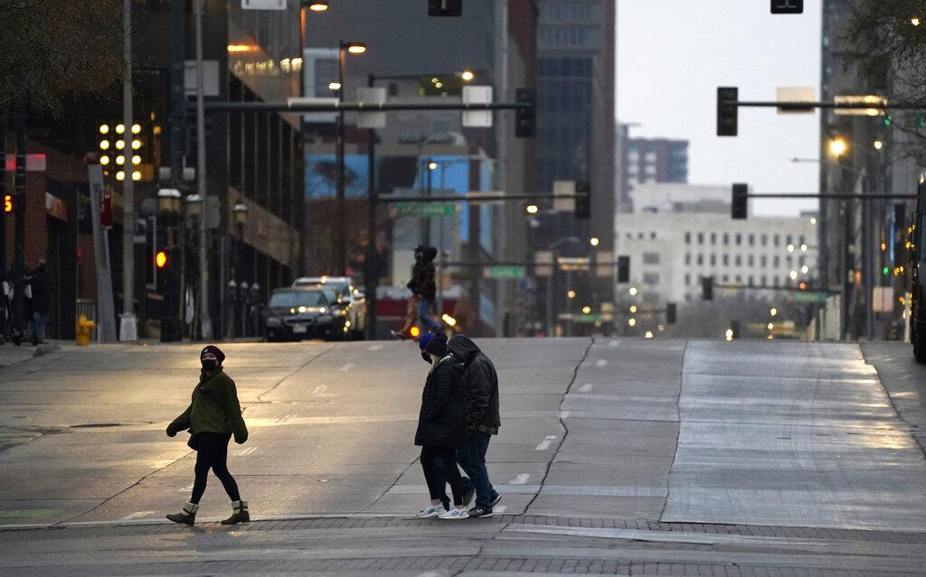 Pedestrians wear masks while crossing an empty road at the intersection of Market Street and 15th Avenue during the evening rush hour Monday, Dec. 28, 2020, in downtown Denver. (AP Photo / David Zalubowski)