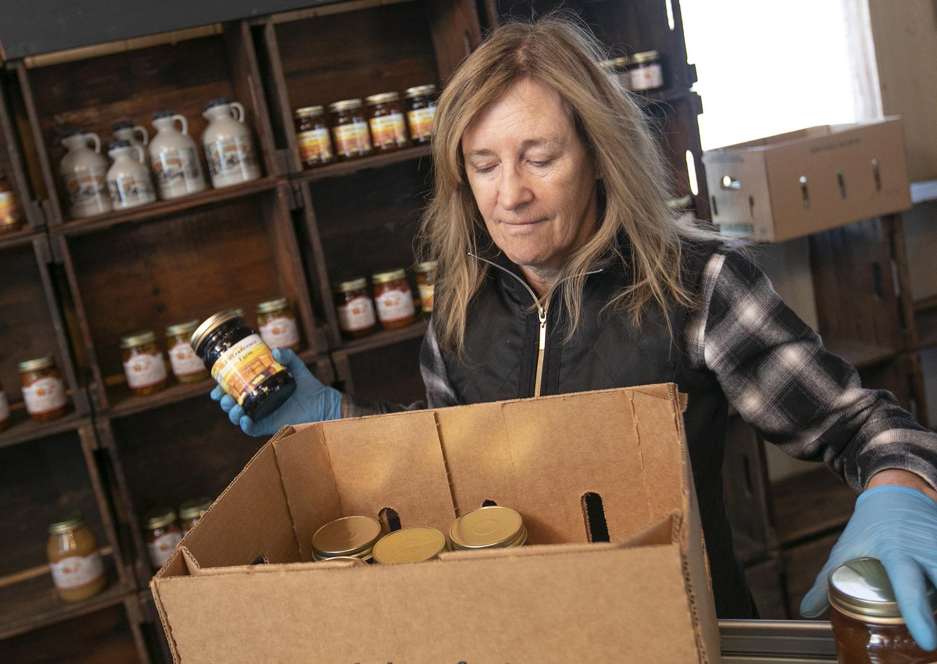 Linda DeFrancesco stocks shelves with her farm’s own salsa, spreads, veggies and salsa at DeFrancesco Farm Stand in Northford, Conn., Thursday, March 26, 2020. (Dave Zajac / Record-Journal via AP)