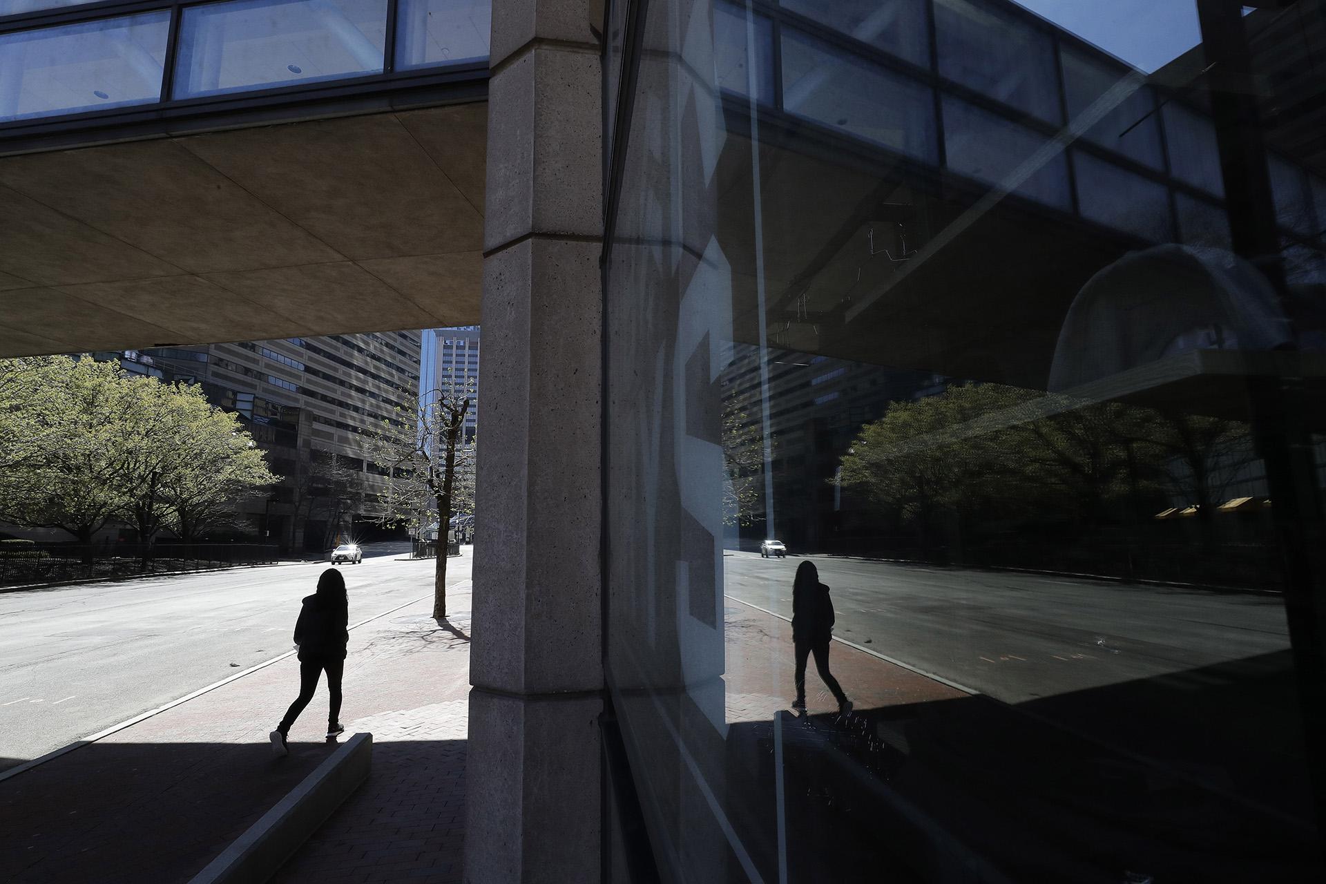 A person walks along a nearly empty street Wednesday, April 29, 2020, in Boston. Job cuts have escalated across the U.S. economy in recent days that remains all but shut down due measures taken to halt the spread of the virus. (AP Photo / Steven Senne)