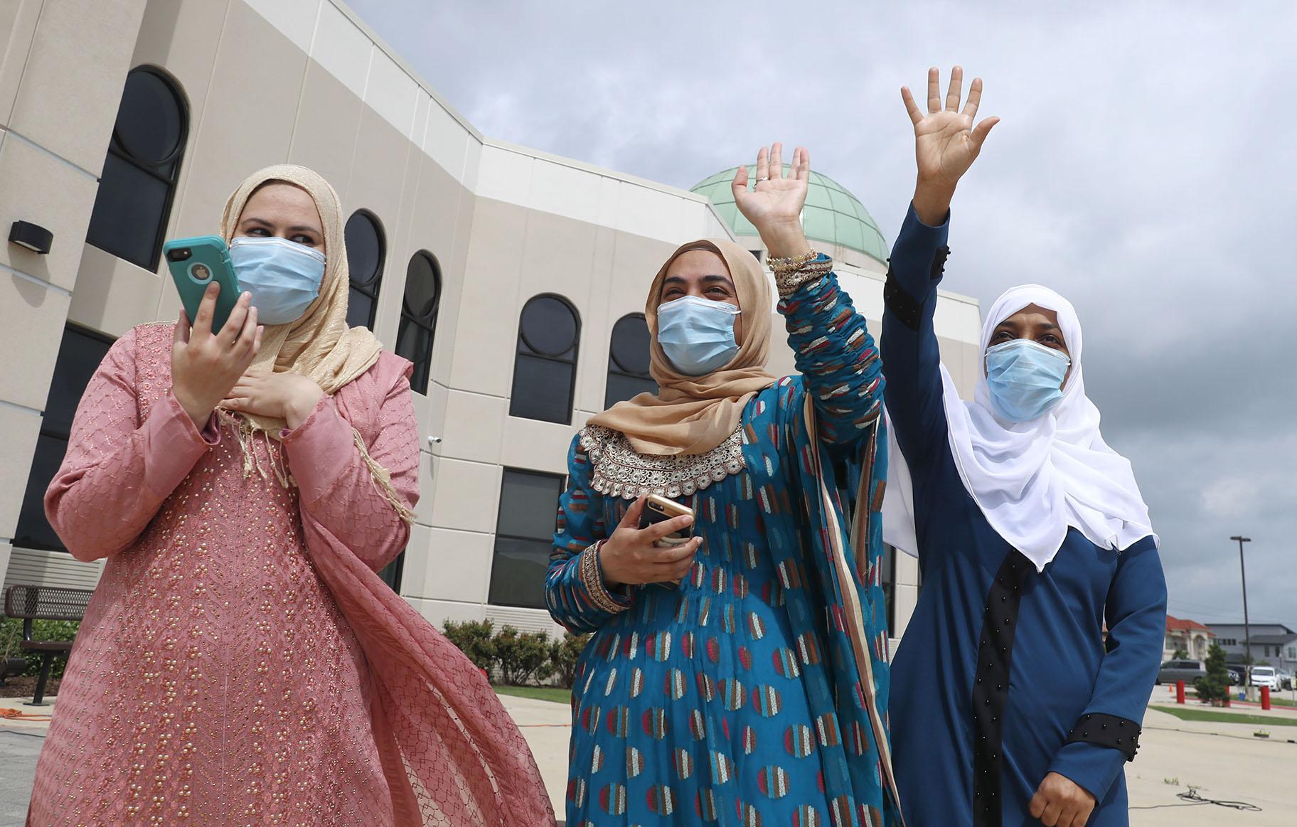 Saba Mahjabeen, right, and Gizman Mawi, center, waive as Sophia Baig looks on during a drive through Eid al-Fitr celebration outside a closed mosque in Plano, Texas, Sunday, May 24, 2020. (AP Photo / LM Otero)